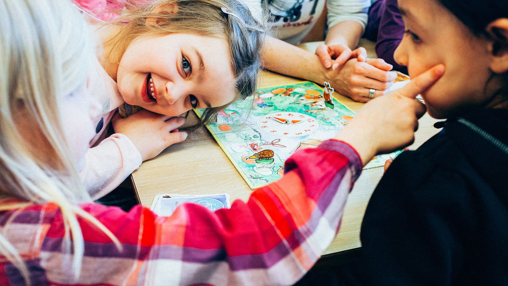 Kindergartenkinder spielen gemeinsam ein Brettspiel, sie lachen.