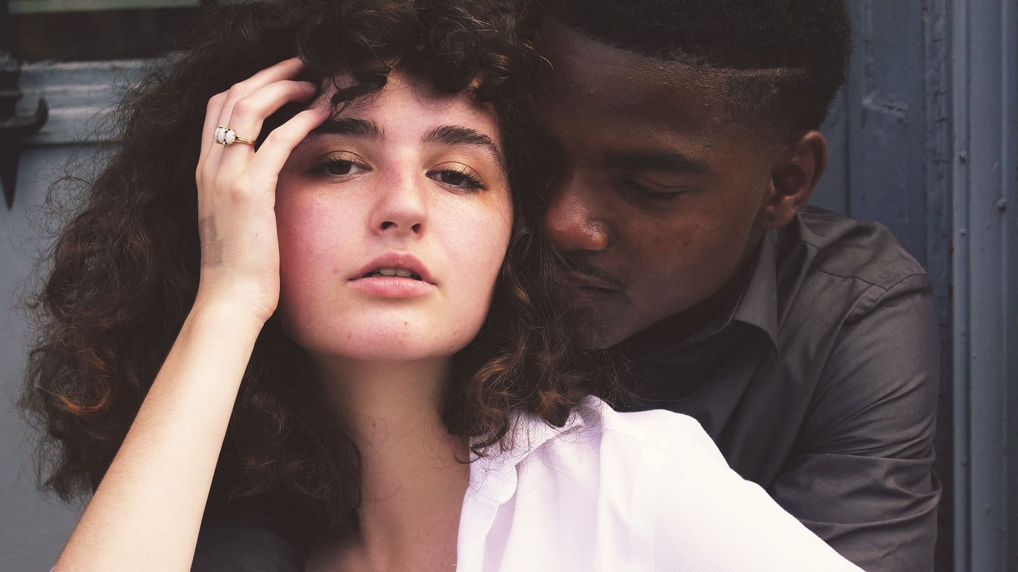 Man sieht ein Paar, ein Mann umarmt mit geschlossenen Augen eine Frau.