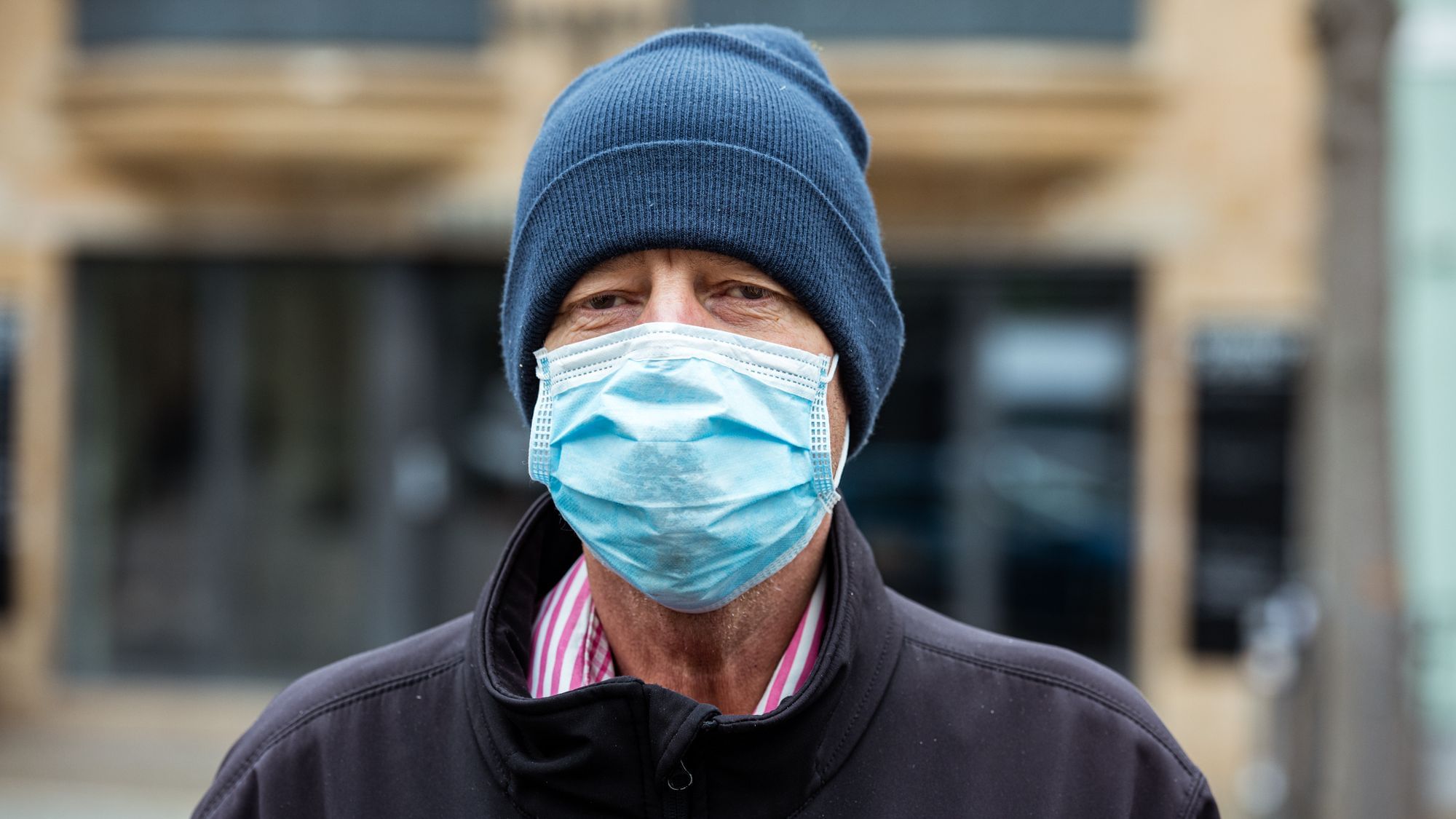 Wir sehen einen Mann mit Mütze, der eine Maske trägt