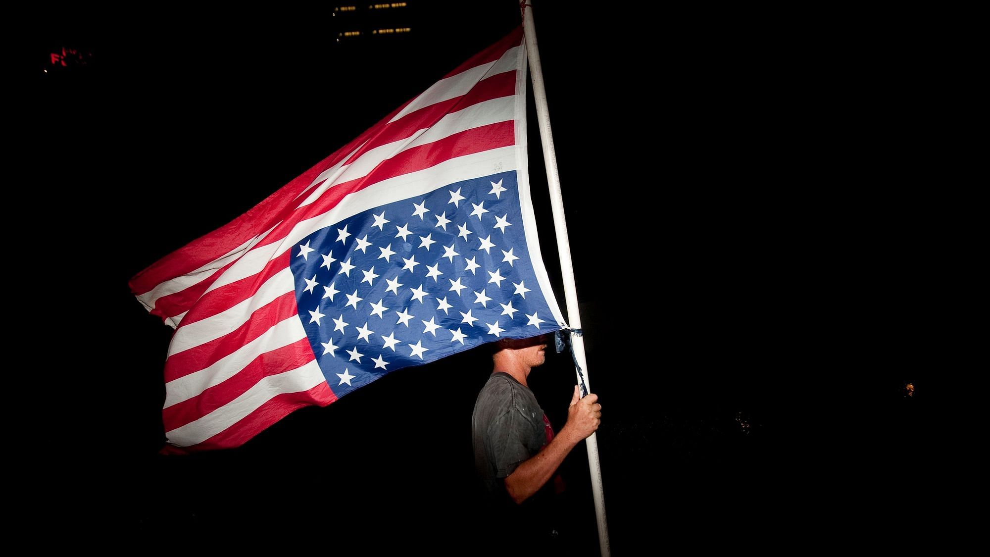 Ein US-Demonstrant trägt eine amerikanische Flagge verkehrt herum, mit den Sternen nach unten und den weiß-roten Streifen nach oben.