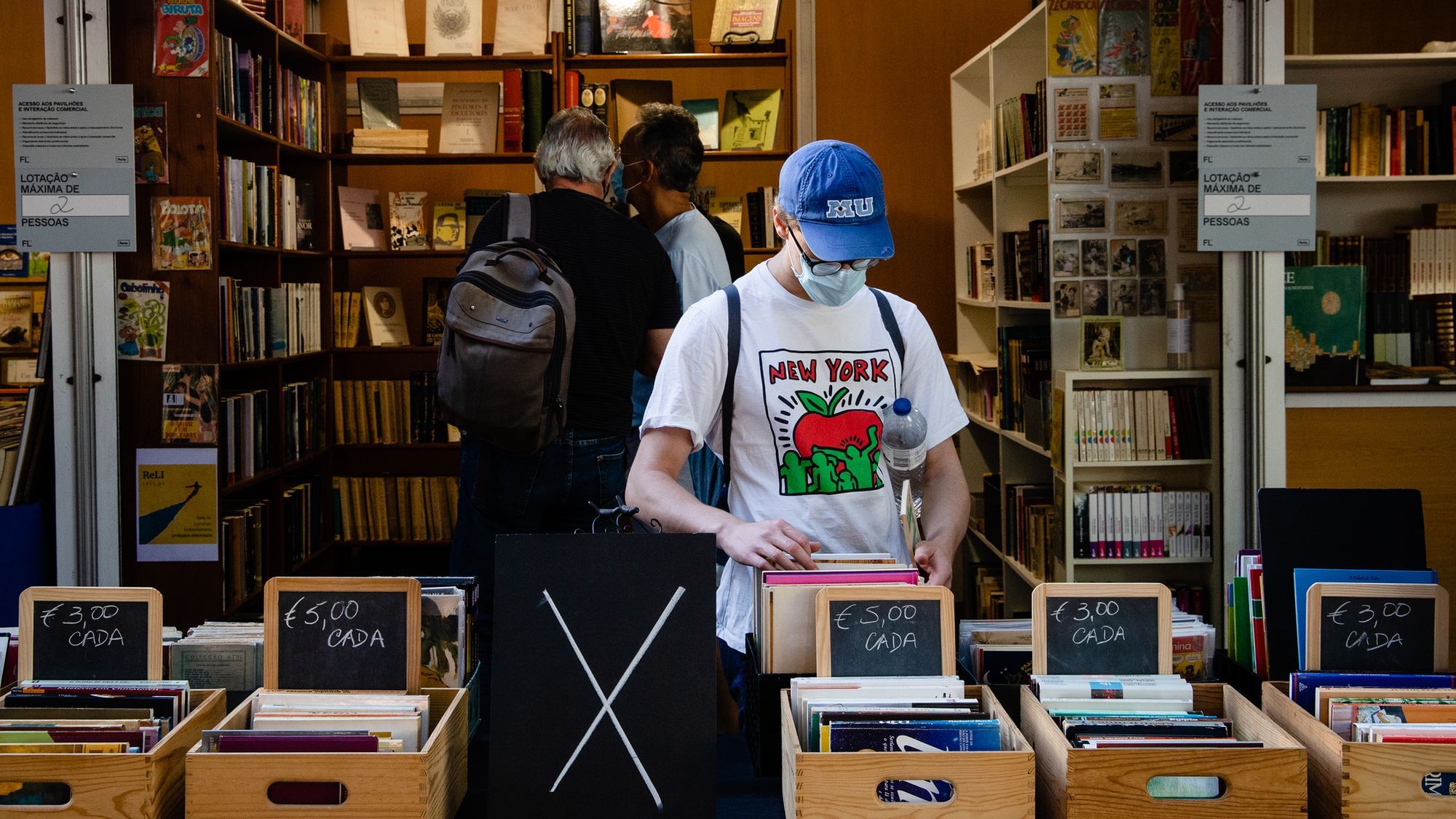 Männlich gelesene Person schaut in Kisten stehende Bücher auf einer Buchmesse in den Gärten des Kristallpalastes am 28. August 2020 in Porto, Portugal. 