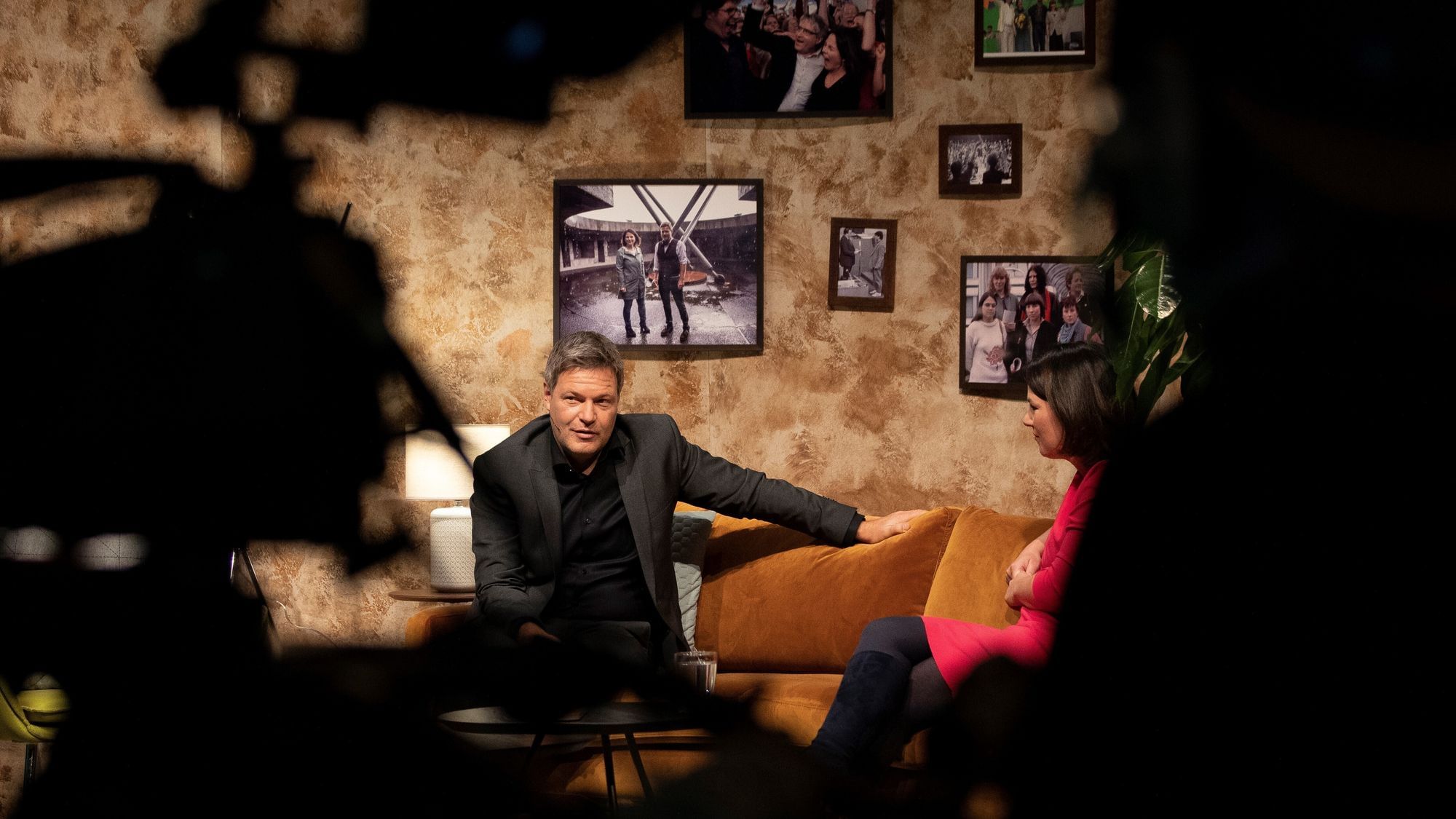Annalena Baerbock und Robert Habeck, die Vorsitzenden der Grünen sitzen auf einem Sofa während der Bundesdelegiertenkonferenz. Vor ihnen sind Kameras zu sehen. 