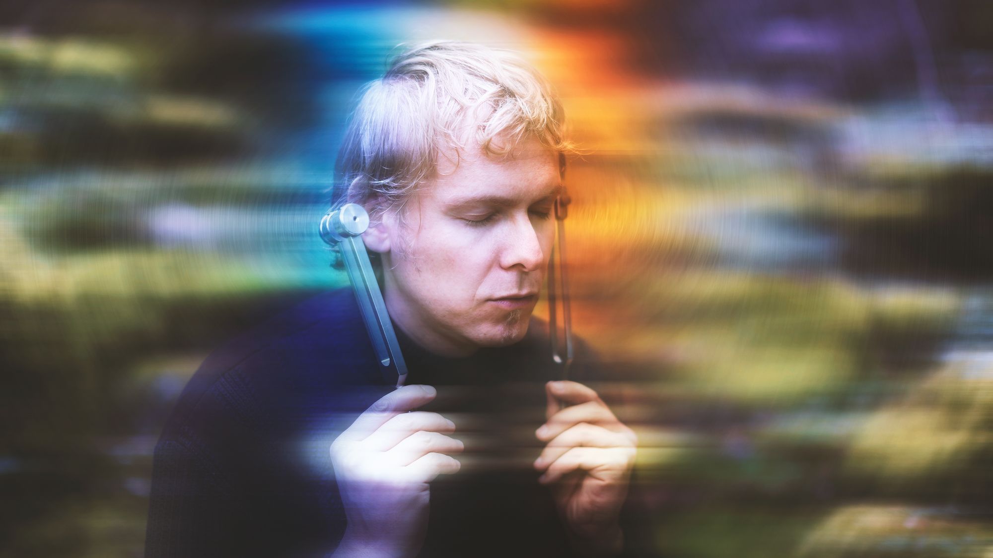 Junger Mann mit Stimmgabel im Wald mit ruhigem Gesicht 