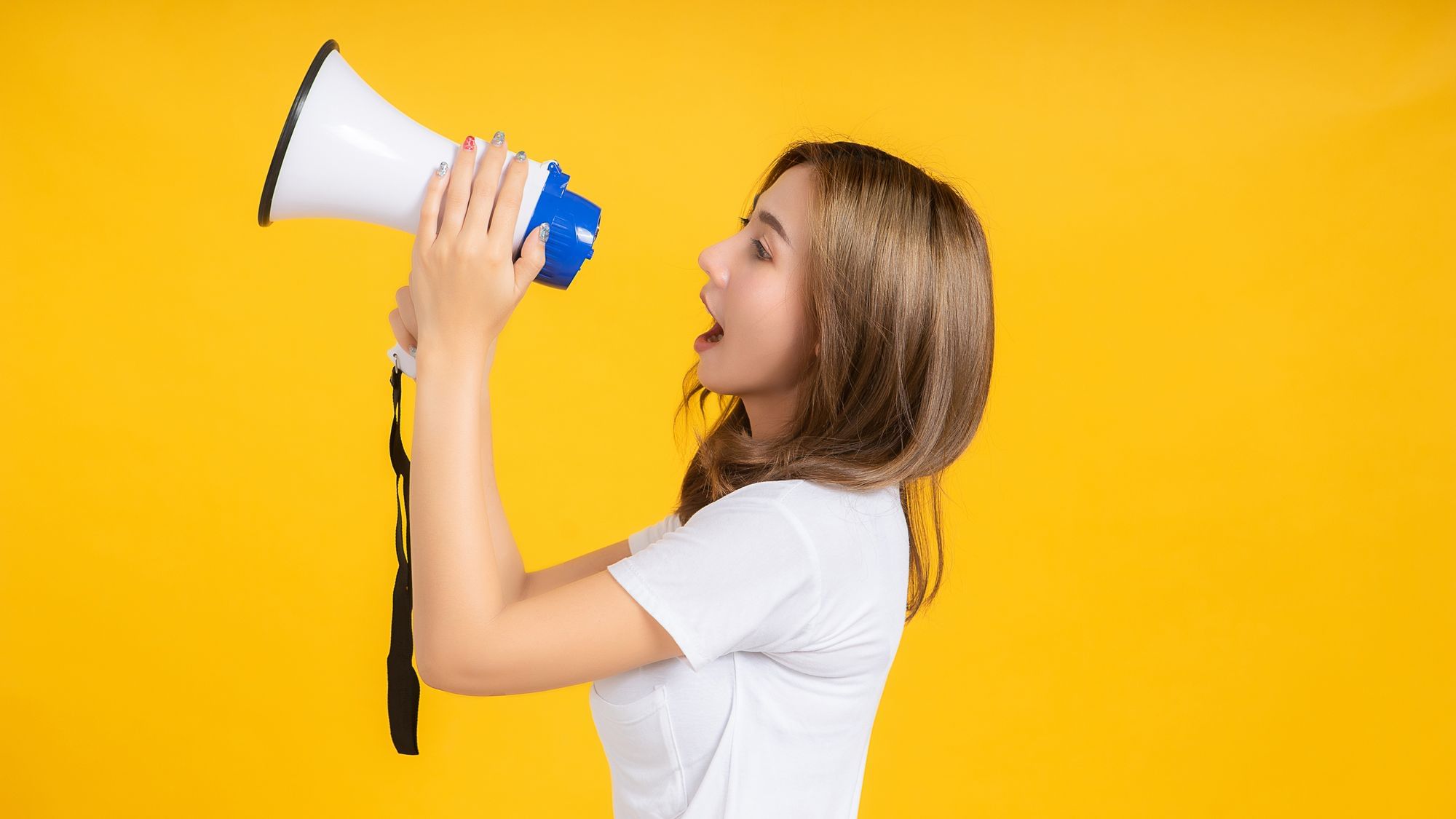 Frau spricht in eine Flüstertüte vor ihrem Mund.