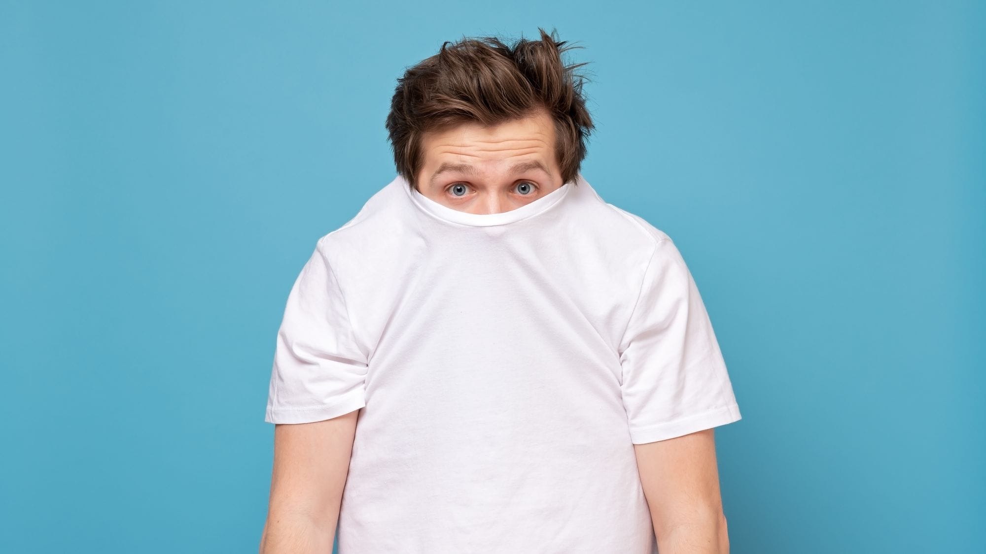 Ein schüchterner Mann, der sich hinter seinem weißen Hemd versteckt.