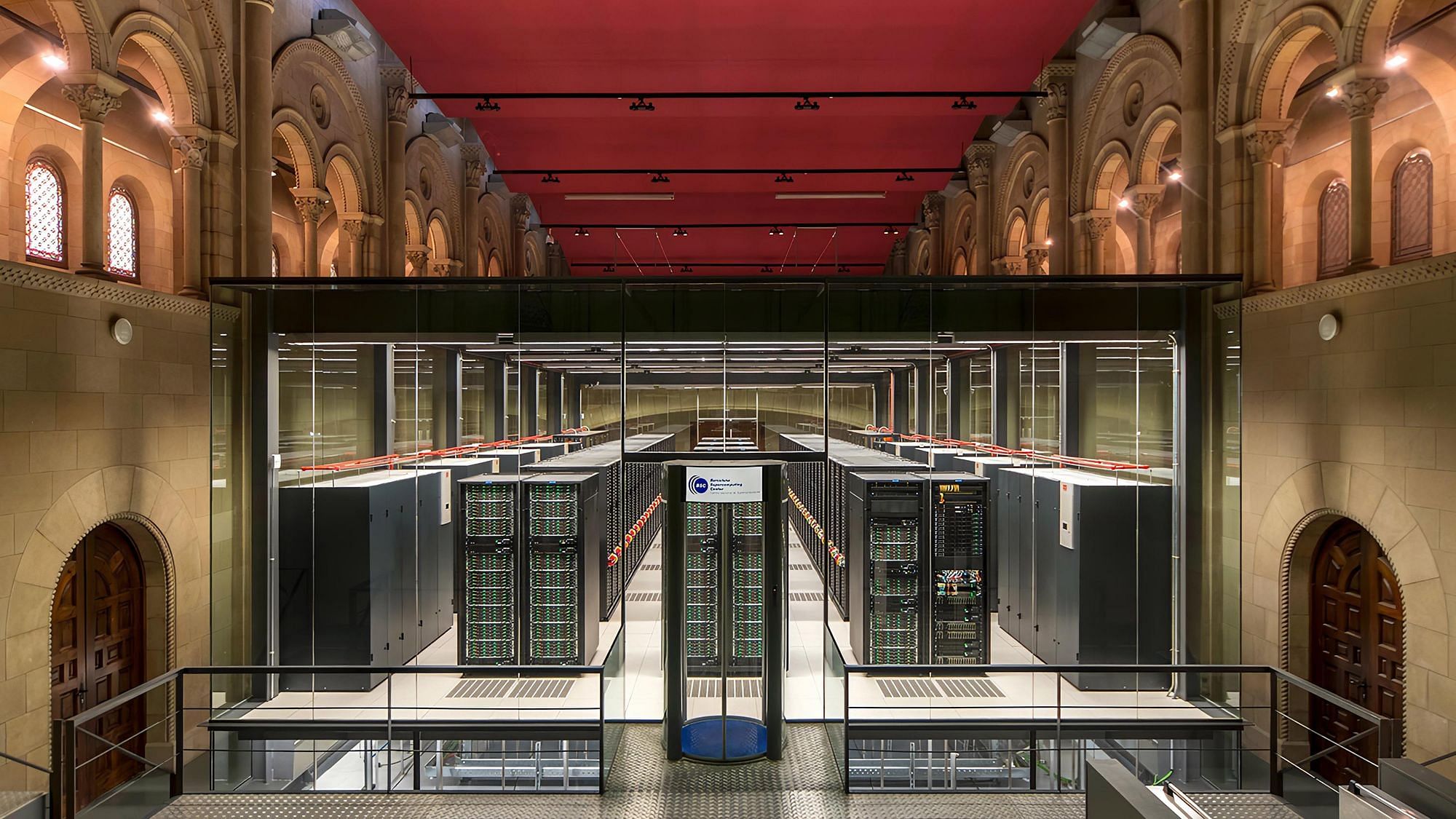 Der Innenraum einer Kirche in der eine Glaskammer aufgebaut ist in welcher Servertürme eines Supercomputers stehen.