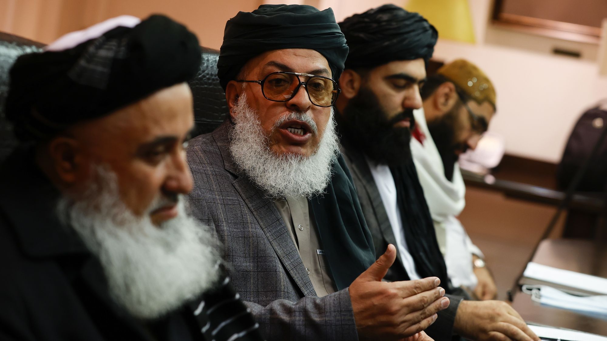 Die Taliban Deligation in Moskau. Eine Reihe Alter Männer mit traditionell Afghanischer Kopftracht, dem Turban ähnlend, mit getönten Brillen diskutieren.