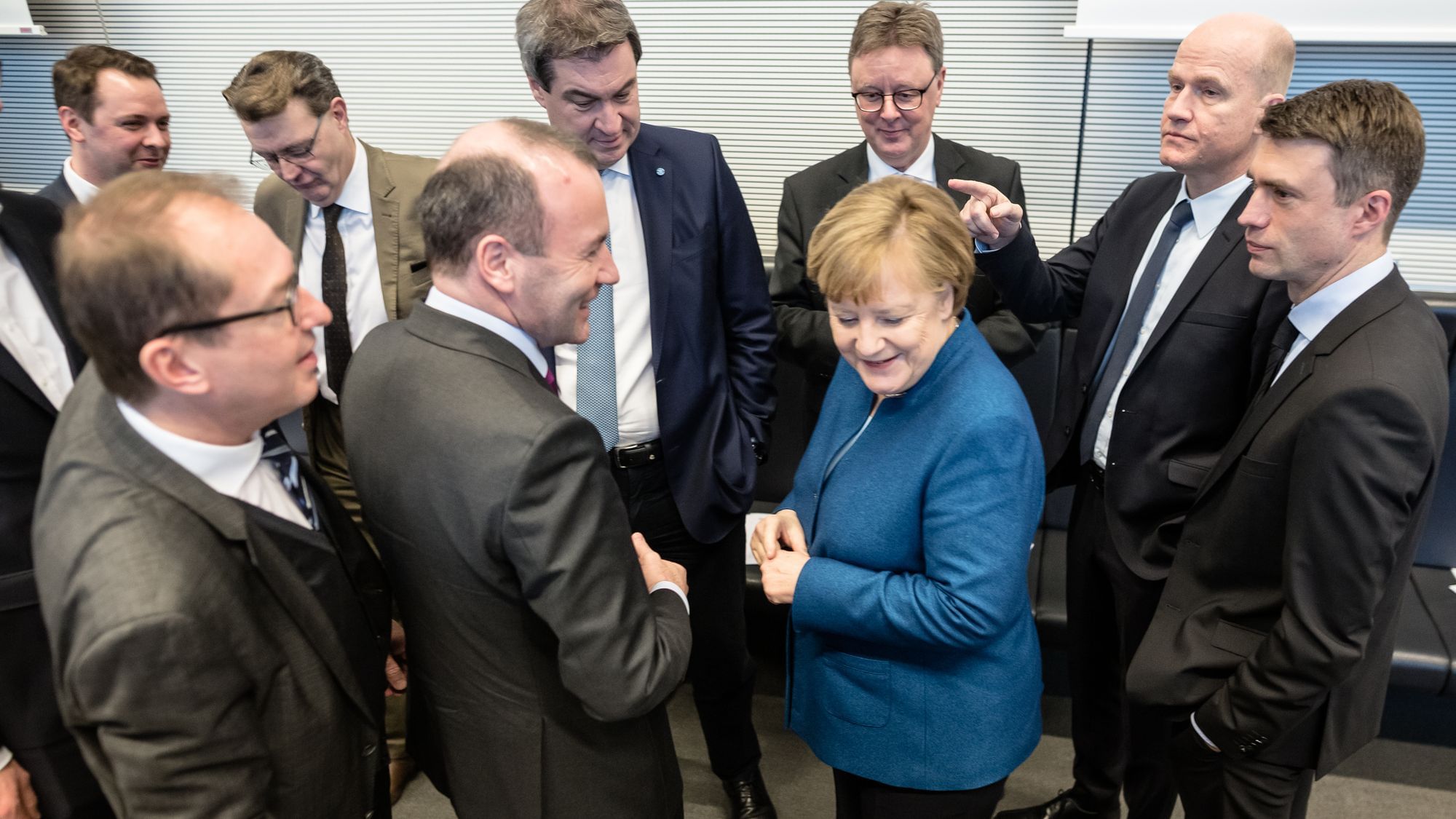 Angela Merkel wendet sich von ausschließlich männlichen Kollegen, die sie umringen, ab. 