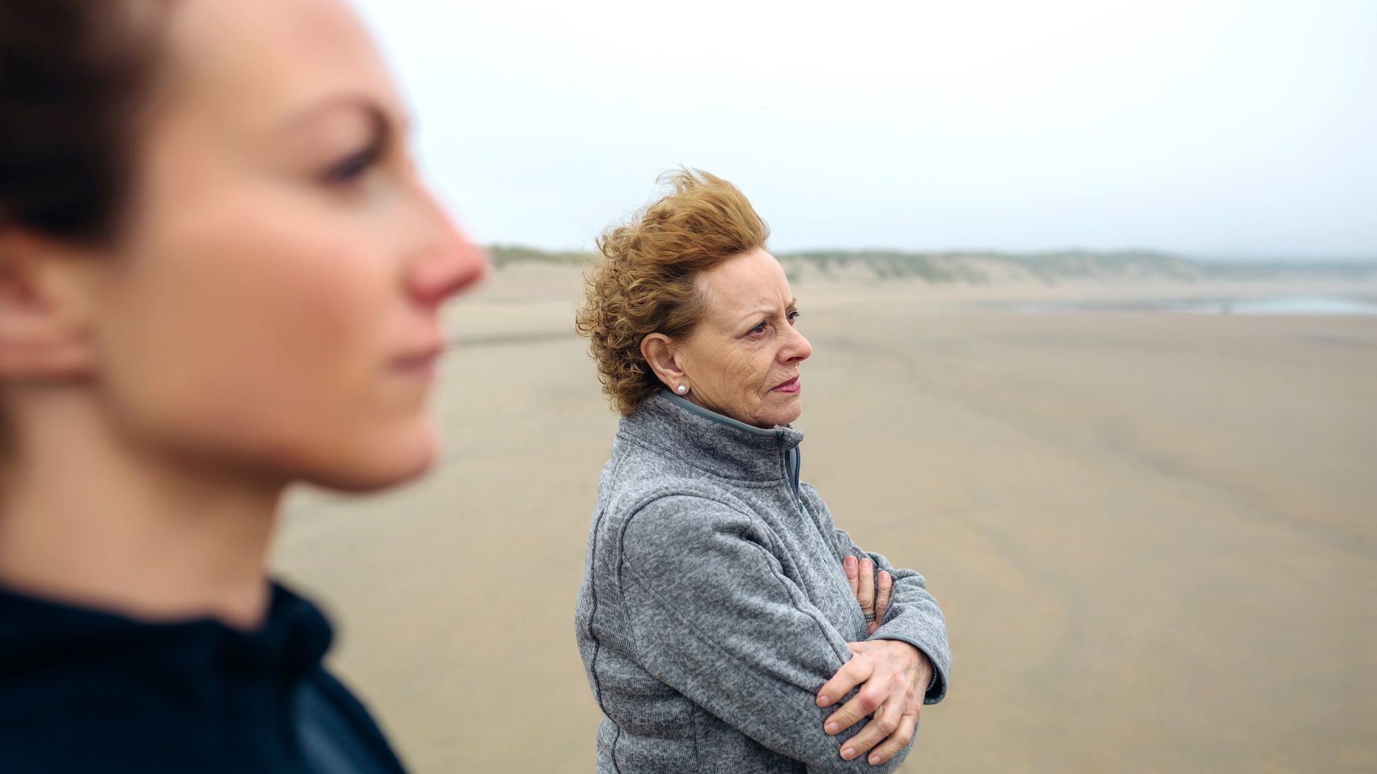 Zwei Frauen stehen am Strand und Blicken in die Ferne
