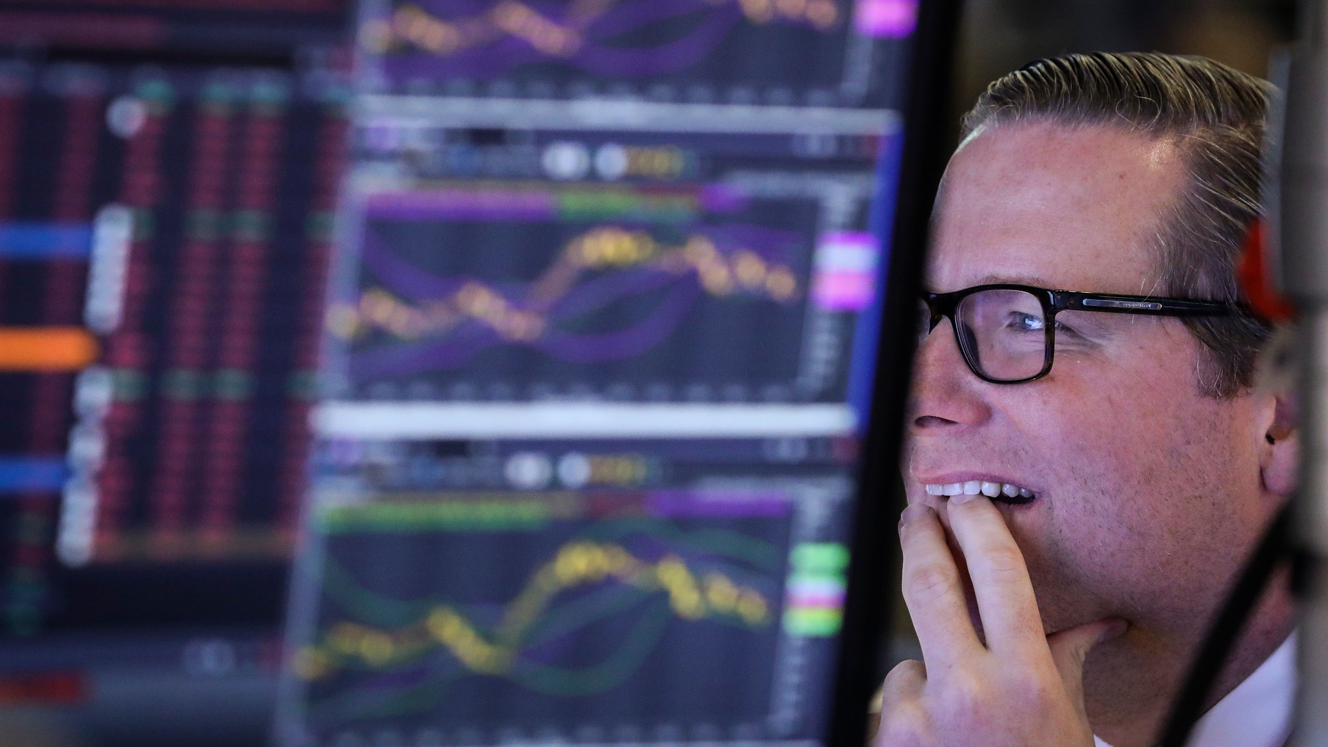 Ein Aktien Makler sitzt an seinem Bildschirm und betrachtet ihn fasziniert.