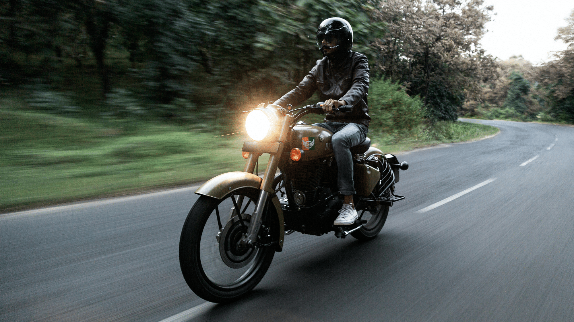 Eine männlich gelesene Person fährt schnell auf einem Motorrad.