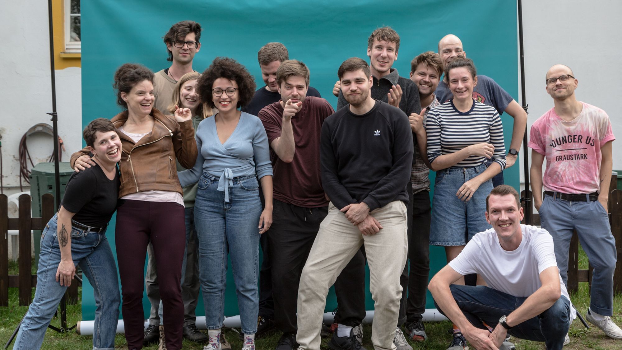 Das sind wir. Wir stehen gemeinsam vor einem türkisen Fotohintergrund.