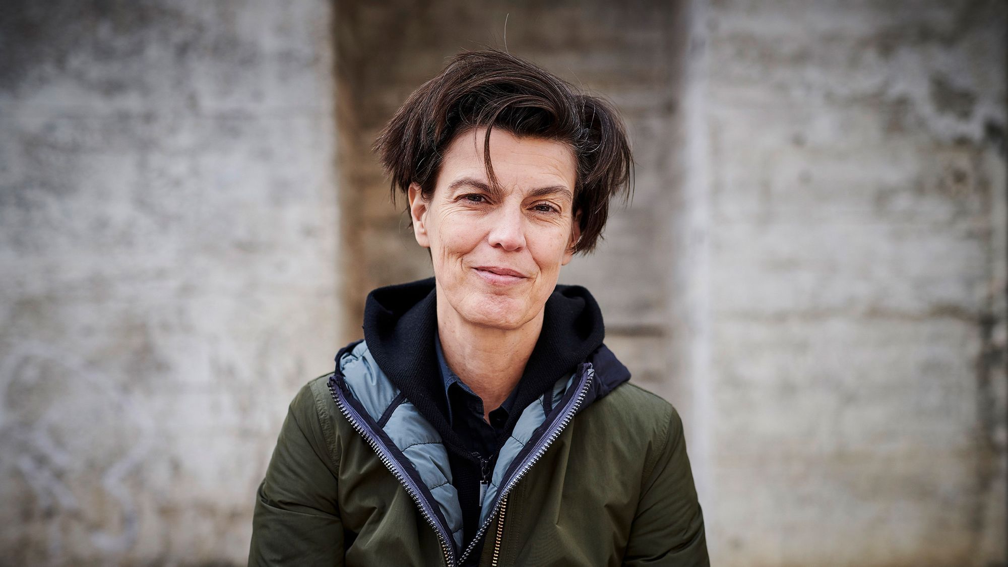 Ein Portrait von Carolin Emcke. Sie trägt eine grüne Jacke und lächelt in die Kamera.