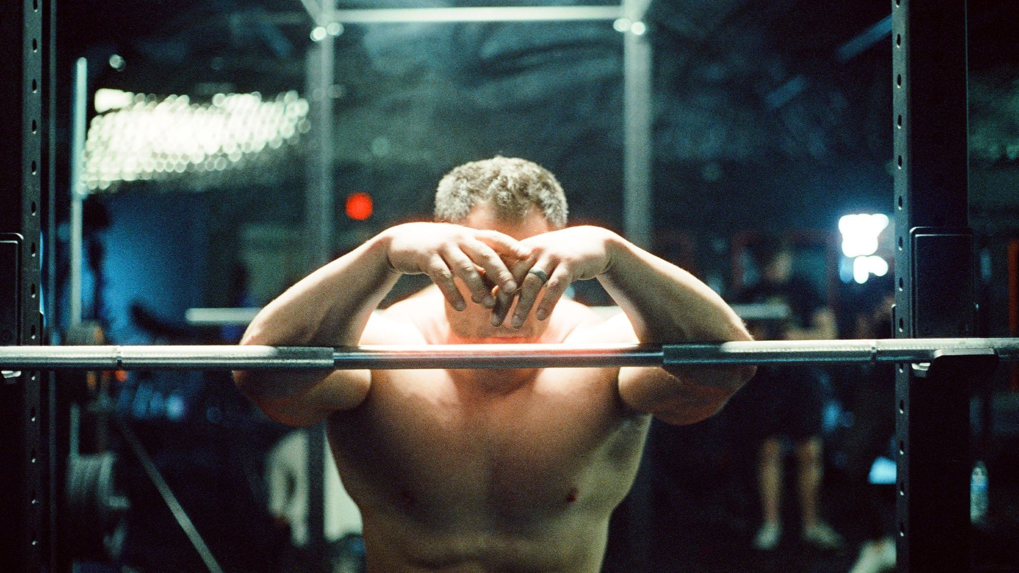 Ein Mann im Fitnessstudio hängt über einer Hantelstange.