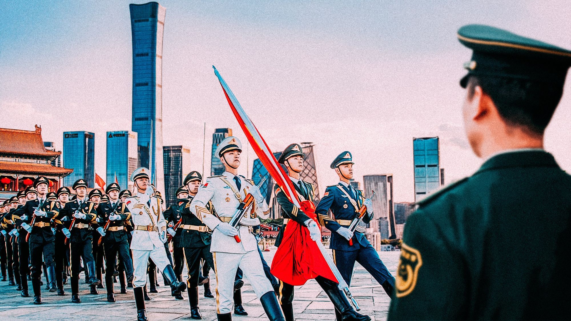 Collage: Ein Mann überwacht eine Militärgarde, an der Front wird eine Fahne getragen. Im Hintergrund ist die Skyline von Peking.