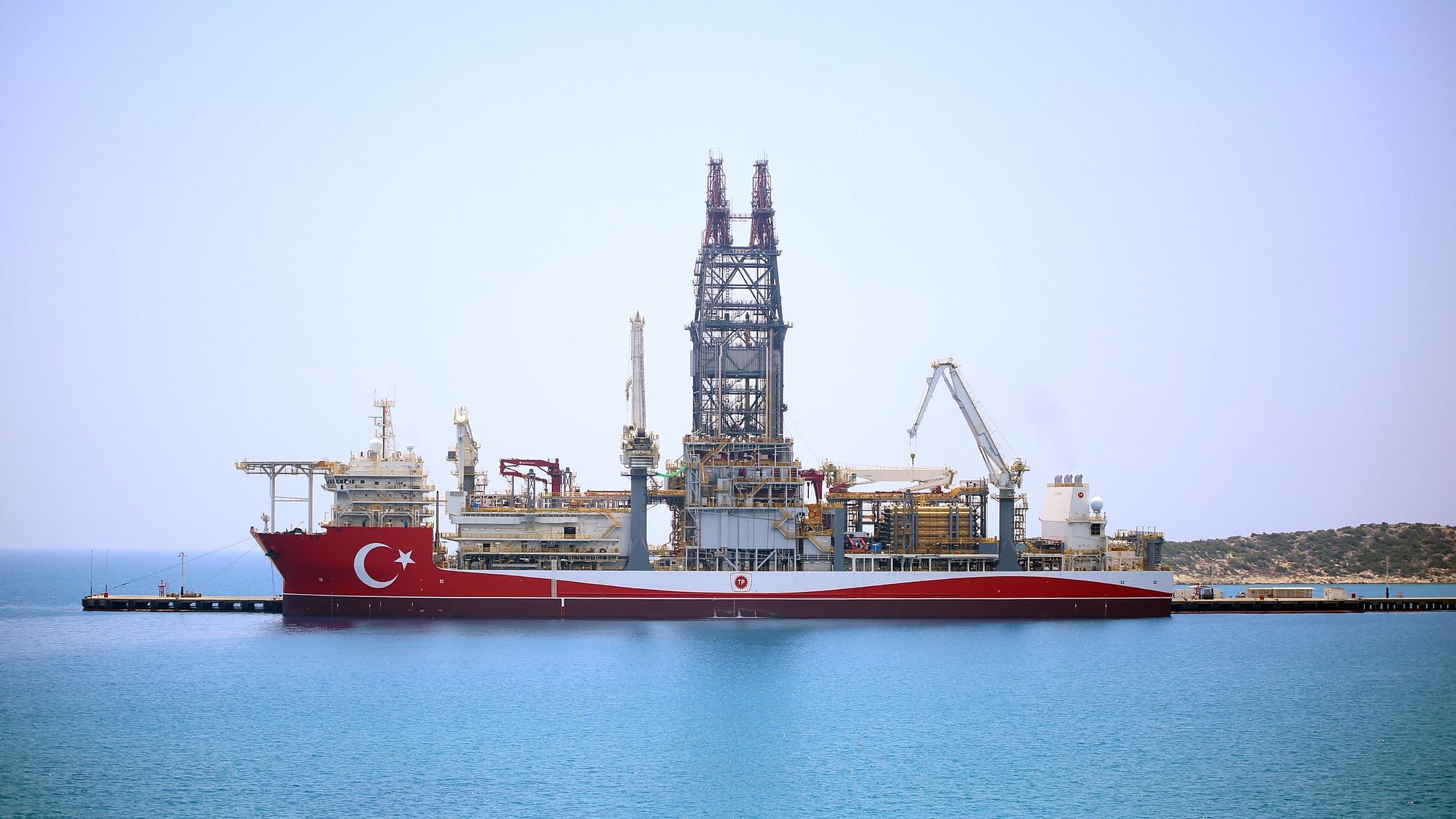 Ein großes Kriegsschiff mit türkischer Beflaggung liegt an einer Mittelmeerinsel an.