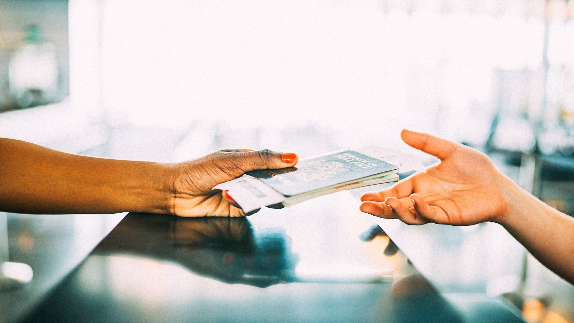 Eine schwarze Hand reicht einer weißen Hand einen Reisepass.