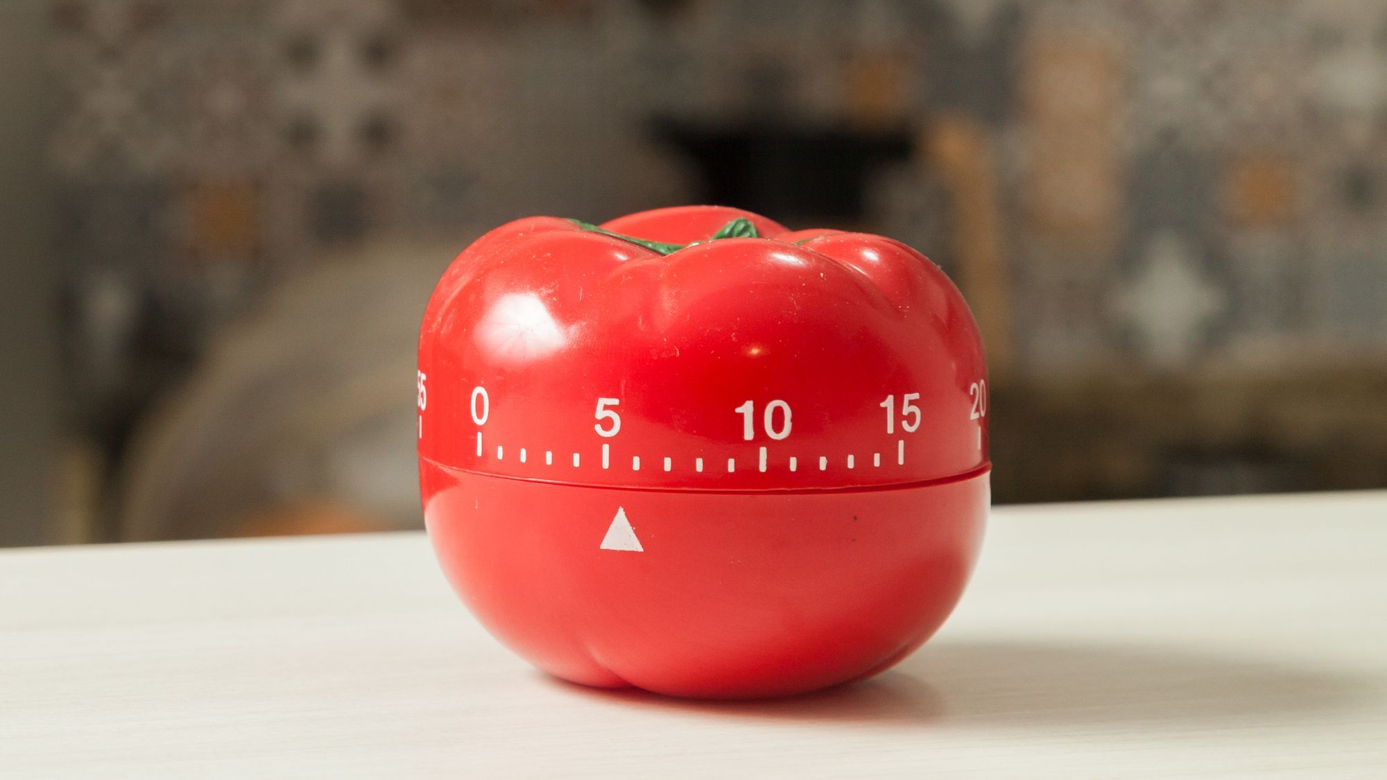 Eine Eieruhr in Form einer Tomate steht auf einer Küchenzeile.