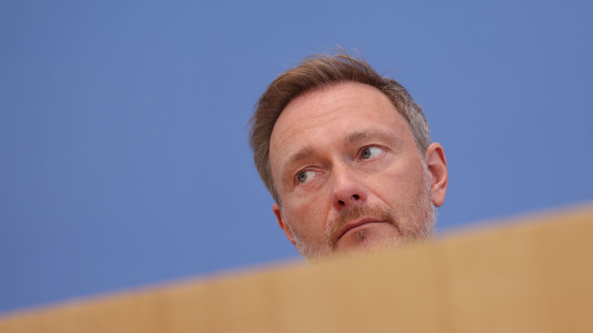 Christian Lindner hinter einer Holzverkleidung.