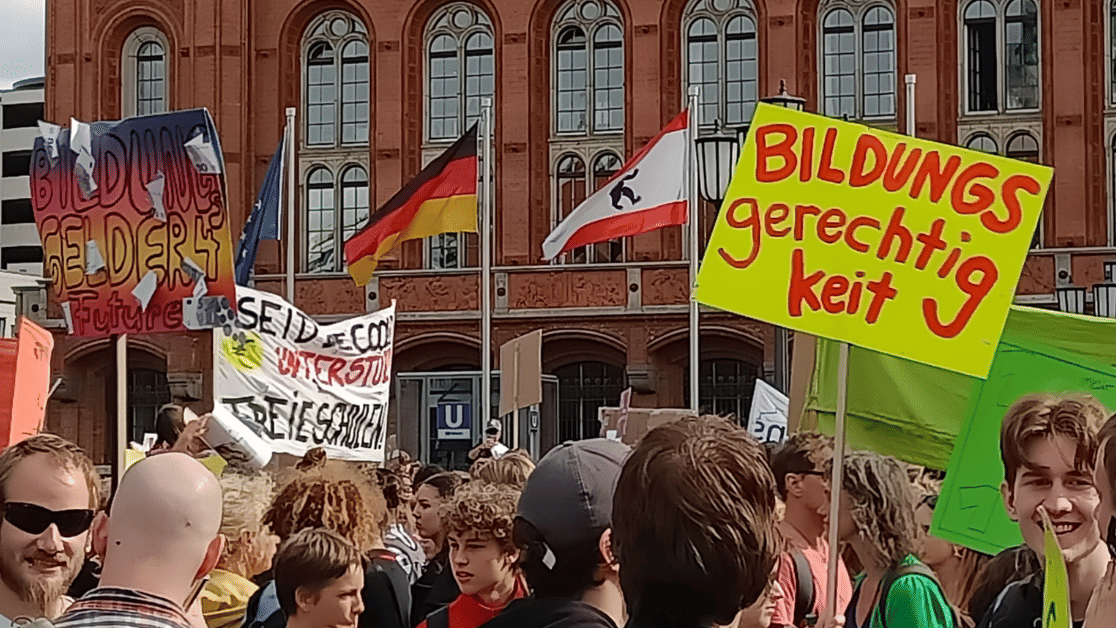Mehrere Menschen, die vor dem roten Rathaus in Berlin Schilder hochhalten. Auf einem steht „Bildungsgerechtigkeit“.