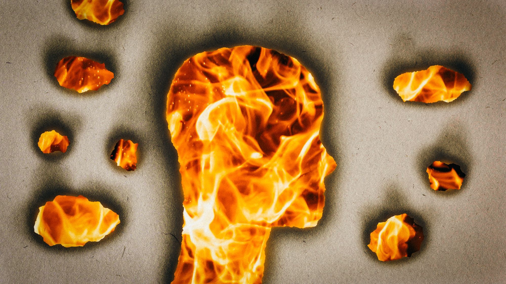 In ein Papier ist ein Brandloch in Form eines Kopfes eingebrannt. Daneben befinden sich mehrere kleinere Brandlöcher. Im Hintergrund sieht man ein Feuer lodern.