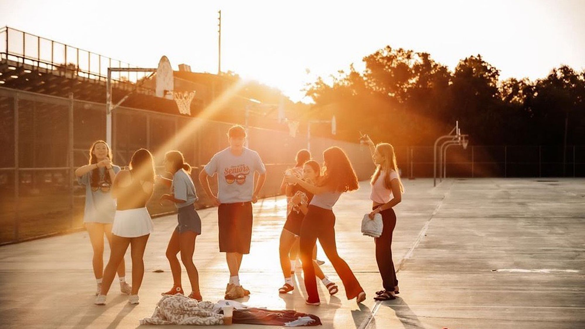 Eine Gruppe von Menschen steht auf einem Basketballplatz bei Sonnenaufgang