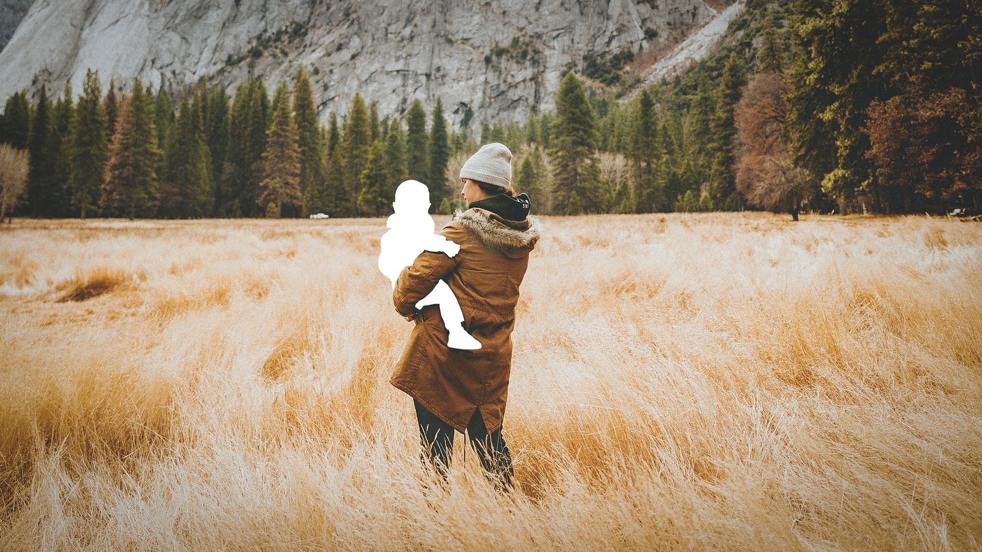 Eine Frau steht in einem Feld. In ihren Armen hält sie die Silhouette eines Kindes.