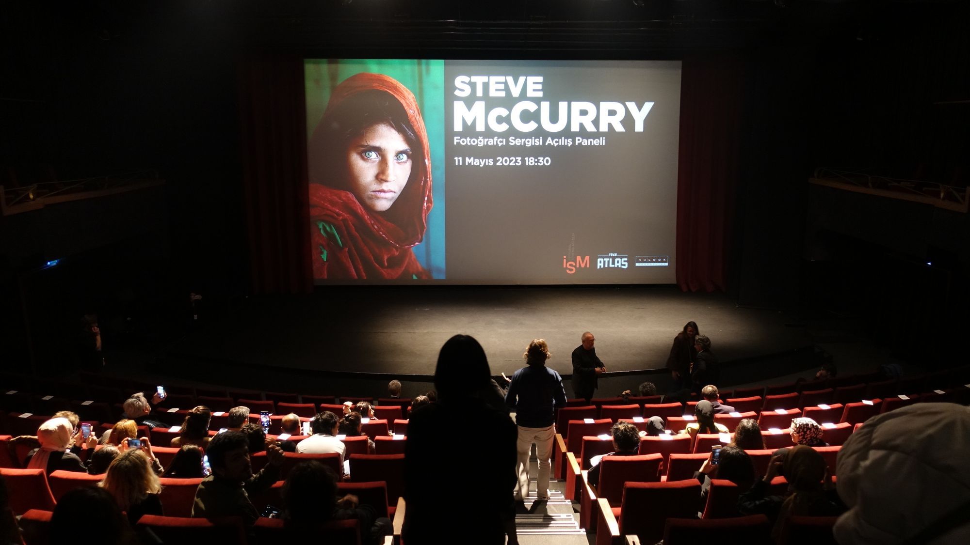 Auf einem großen Bildschirm ist das Foto von Sharbat Gula zu sehen, daneben steht in gr0en Buchstaben „Steve McCurry“.