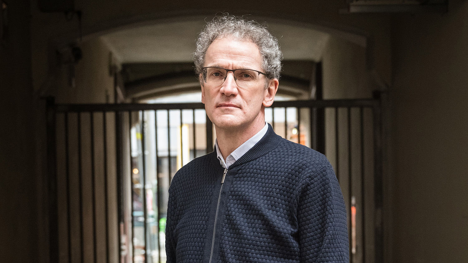 Dirk Oschmann, ein Mann mit grauen Locken und Strickjacke