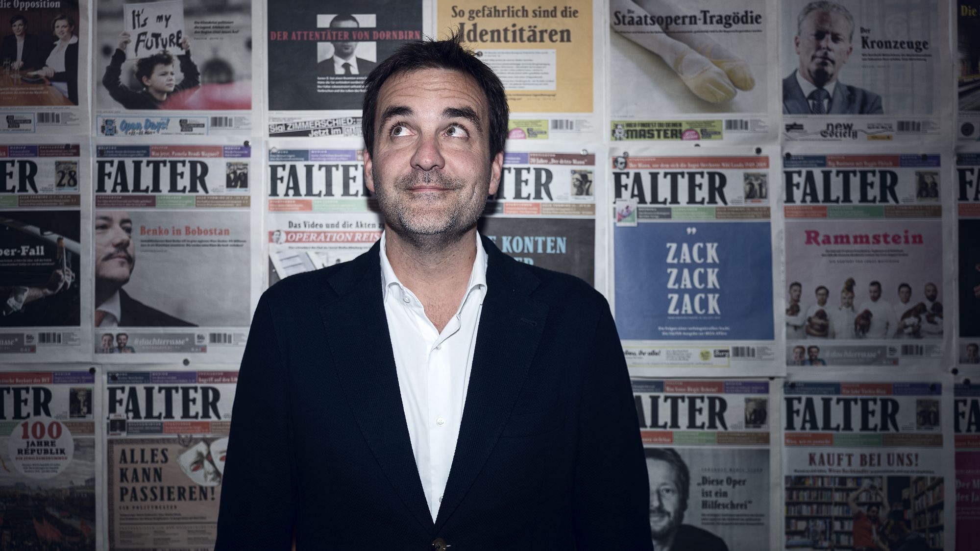 Florian Klenk steht vor einer Wand mit Falter-Ausgaben.