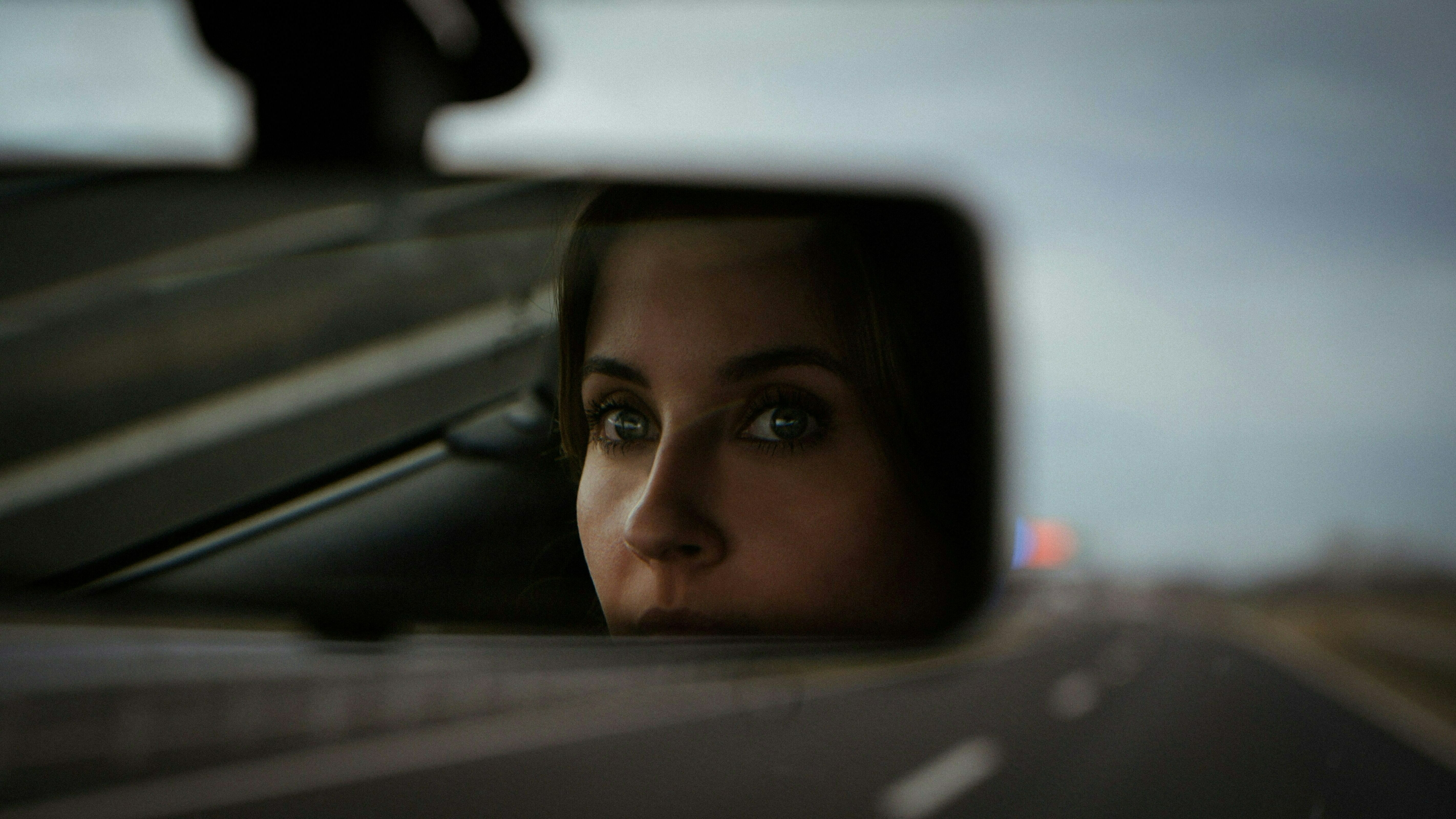 Fotomontage: Theresa Bäuerlein blickt den Betrachter durch den Rückspiegel eines Autos an.