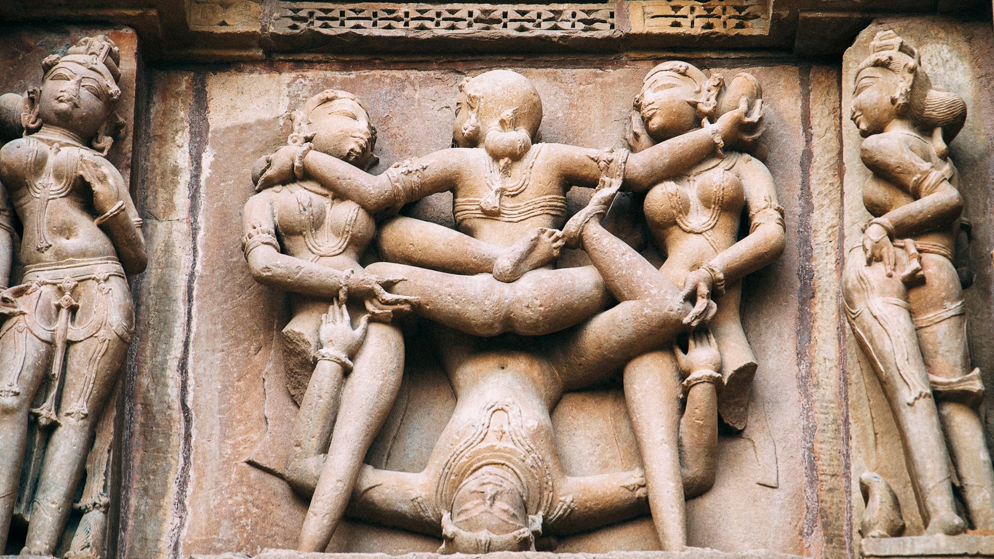 Aus Stein gemeißelte Statuen an der Wand eines indischen Tempels. Sie vollziehen sexuelle Handlungen.