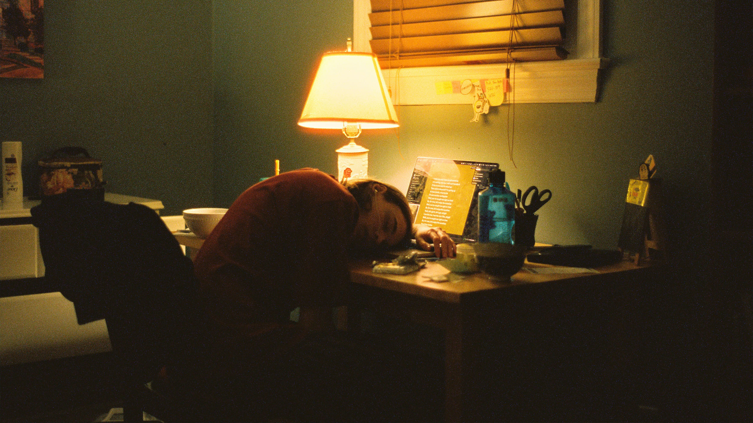 Eine Person liegt auf ihrem Schreibtisch vor dem Computer
