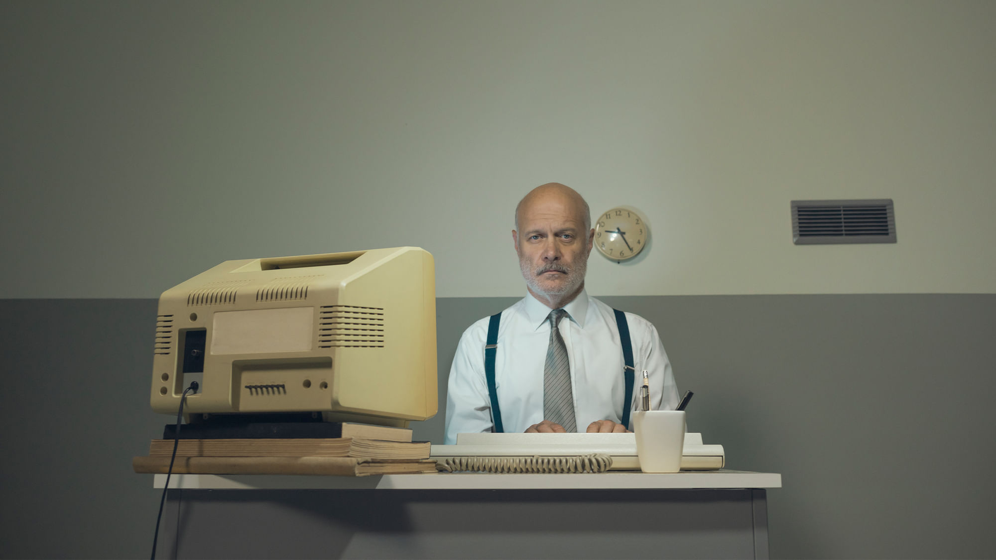 Ein Mann vor einem grau-beigen Bildschirm. Er sieht lethargisch aus.