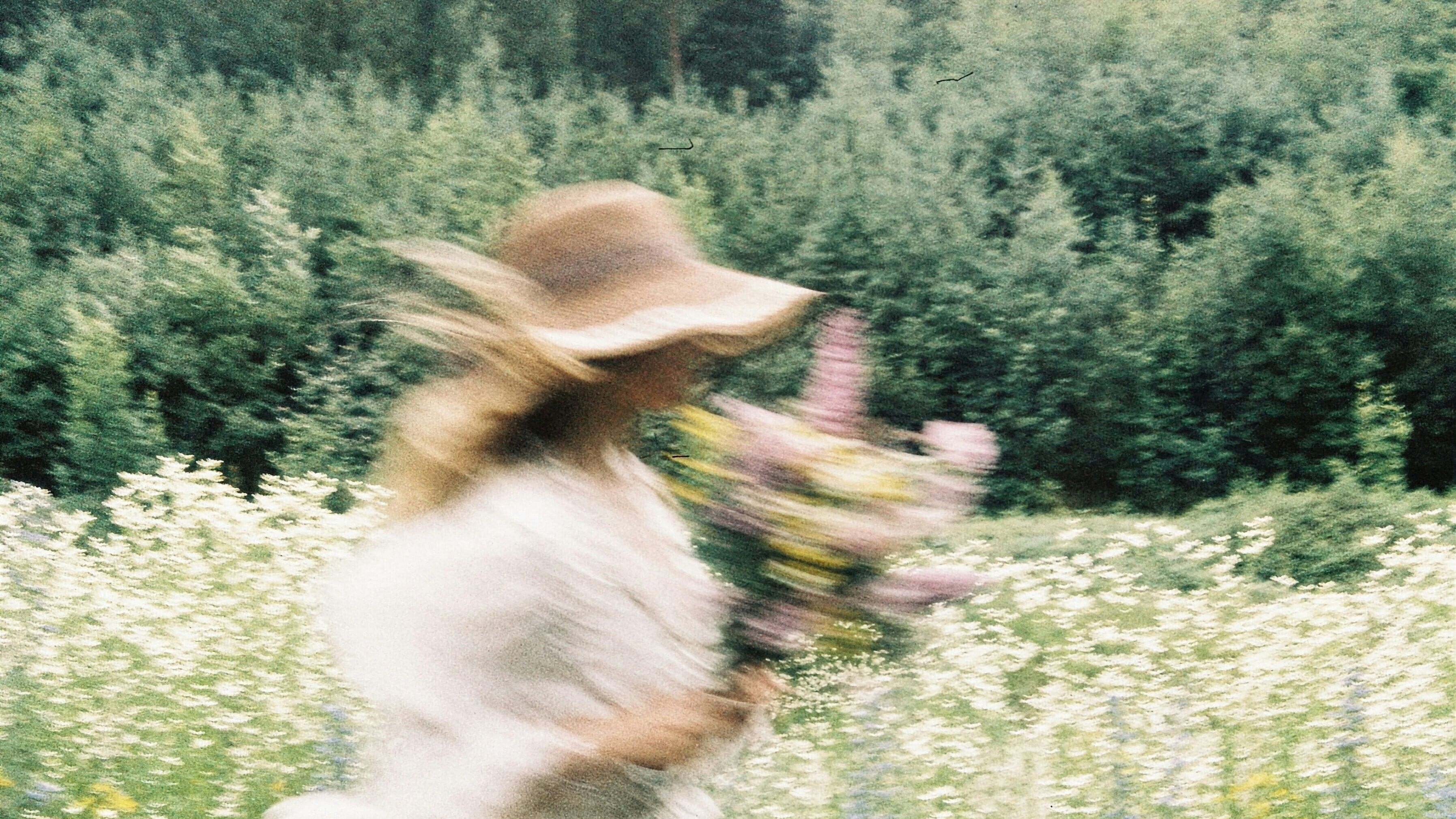 Weiblich gelesene Person in einem Blumenfeld 
