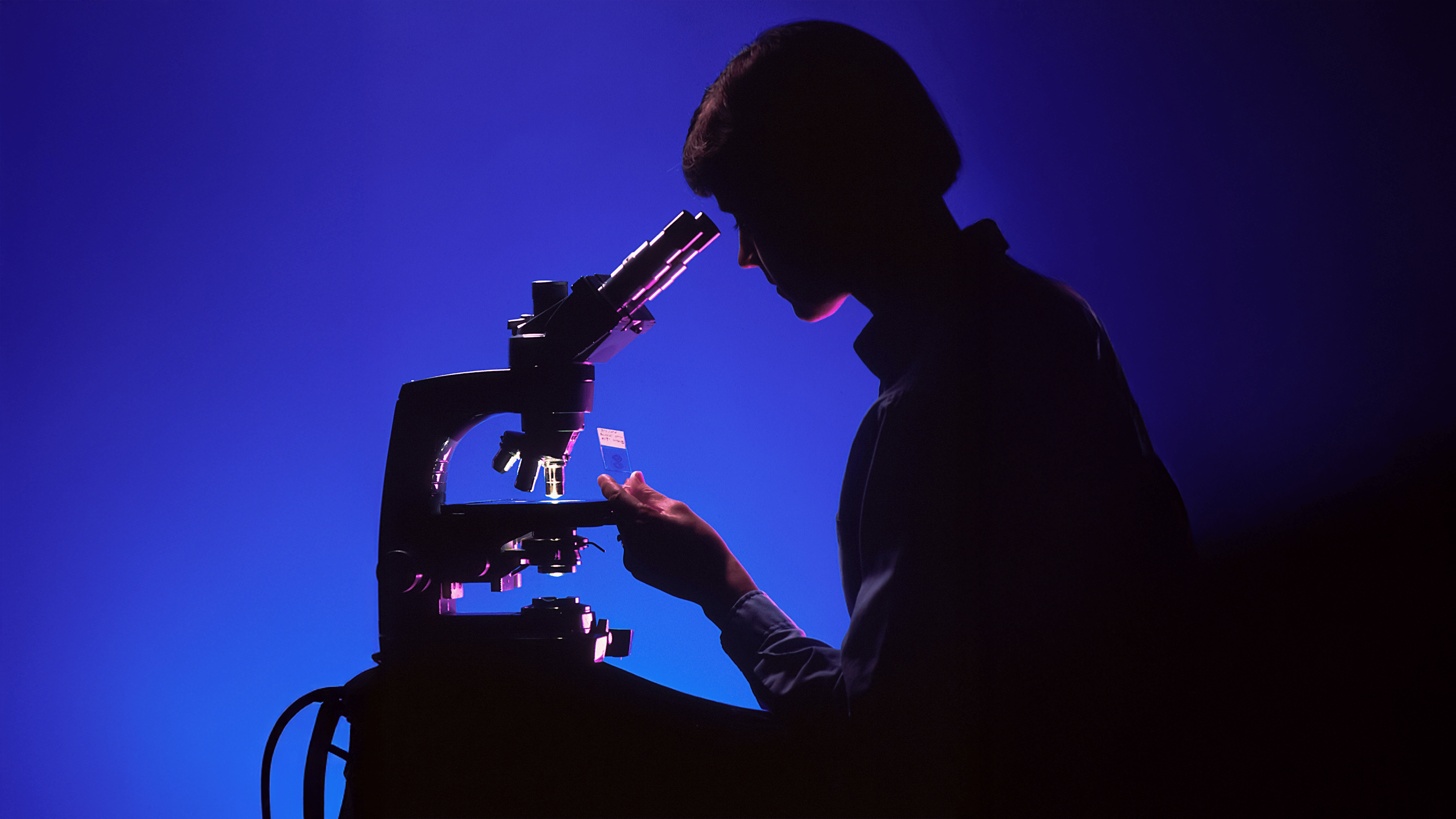 Person die durch ein Mikroskop schaut