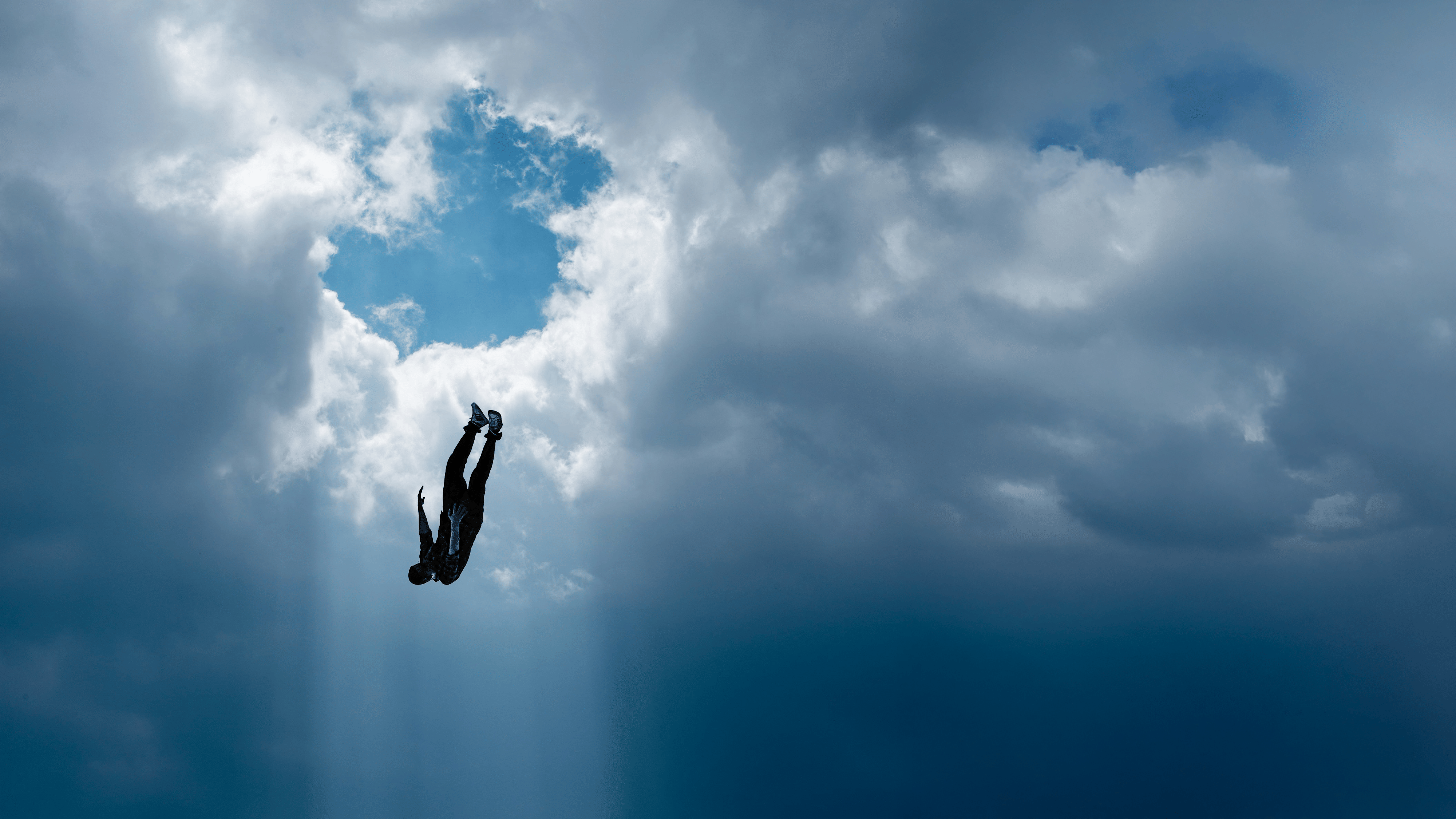 Person die durch die Wolkendecke fällt.