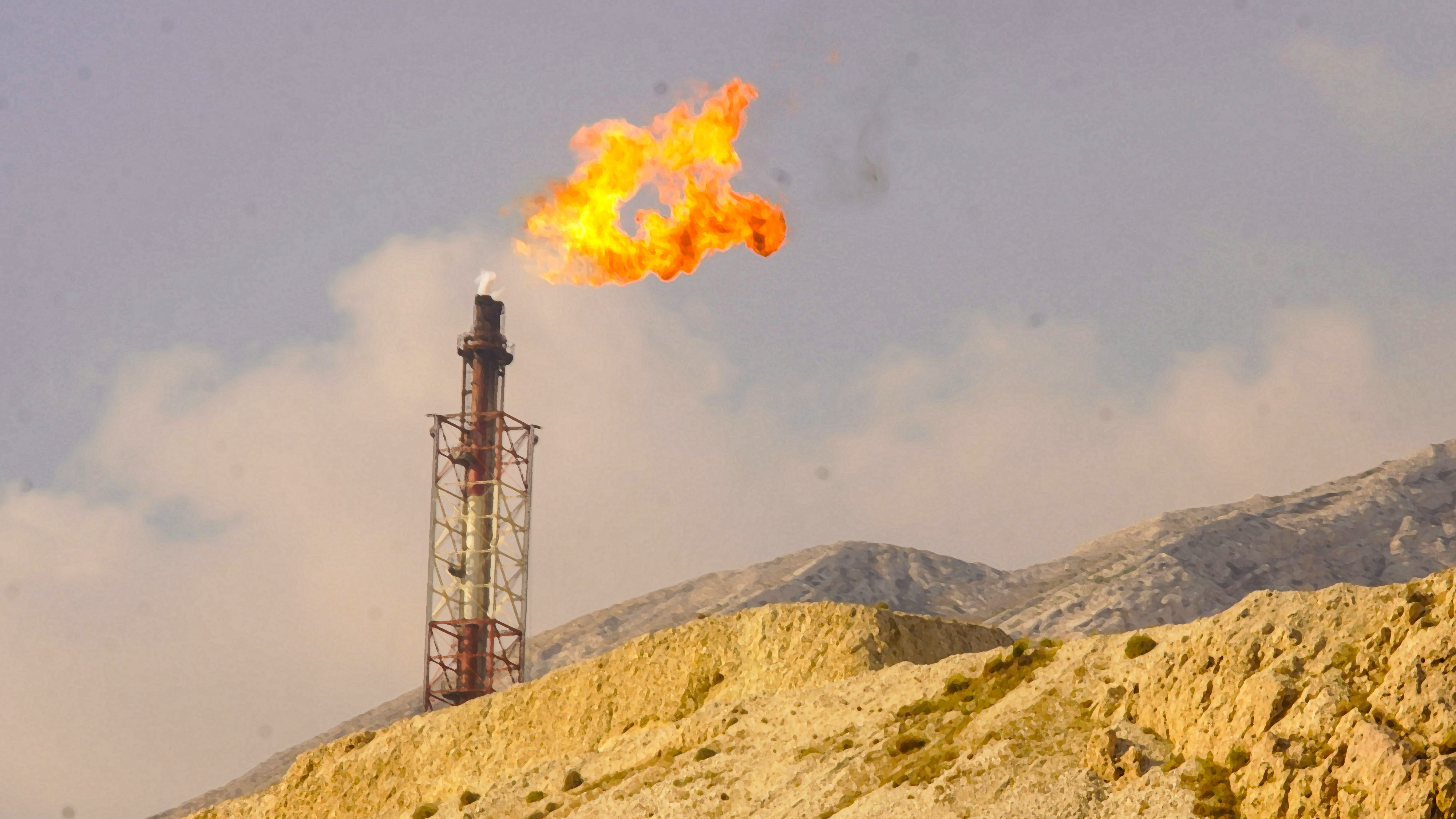 Aktiver Turm einer Anlage zur Verbrennung des Gasüberschusses hinter eines steinigen Bergkammes