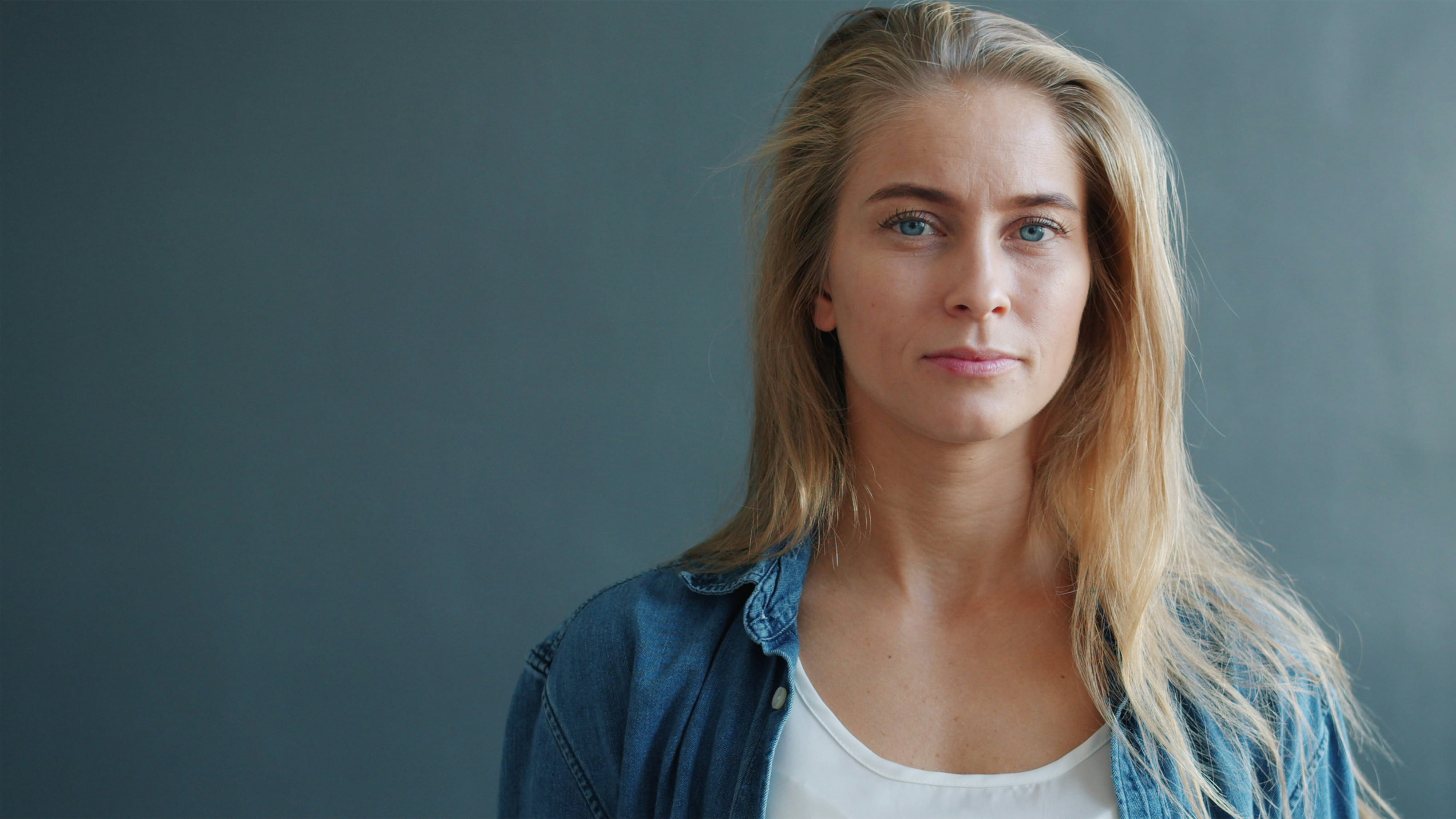 Portrait einer Frau die direkt in die Kamera schaut vor neutralem Hintergrund