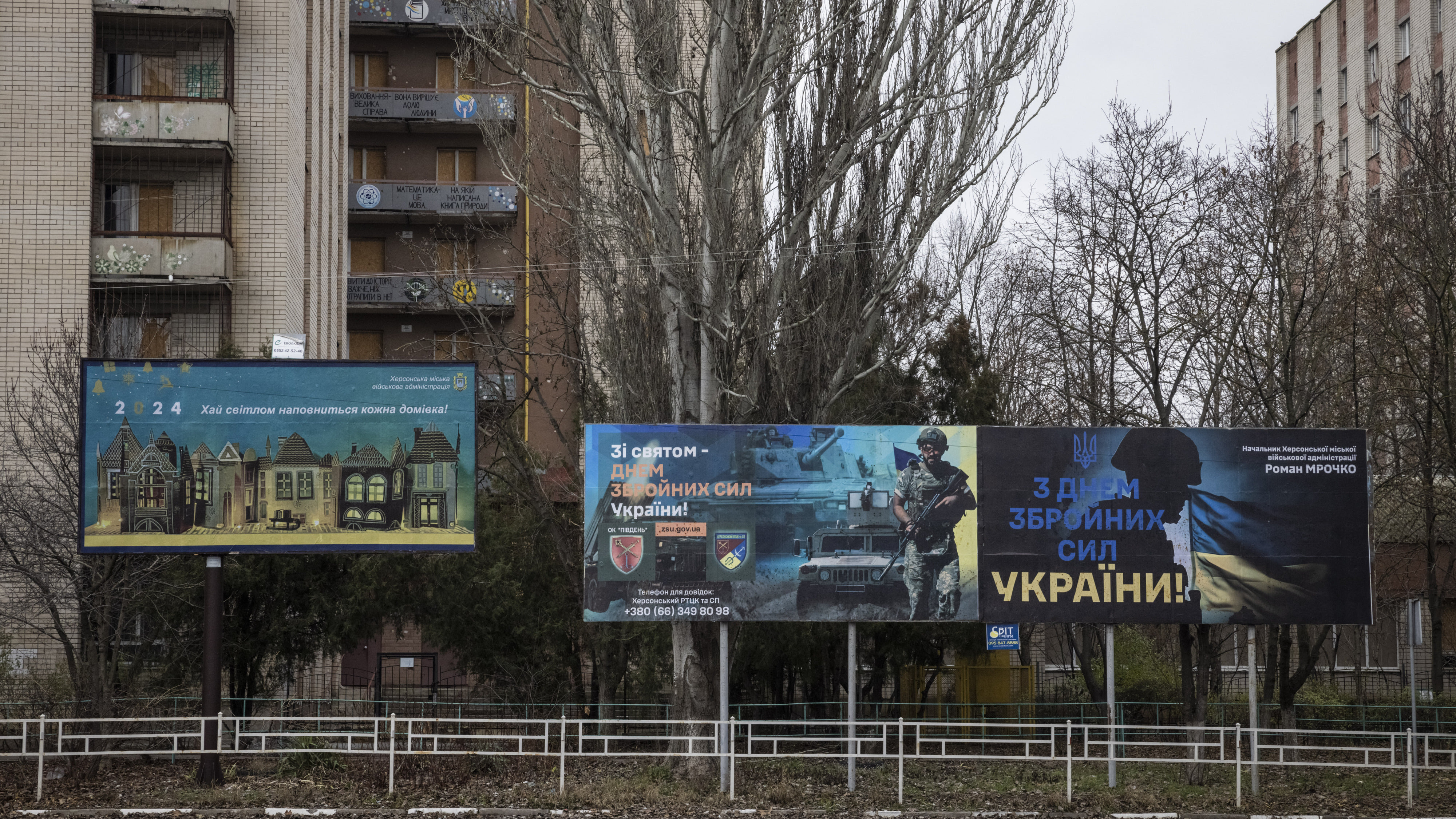 Drei große Plakatwände vor einer Häuserwand.