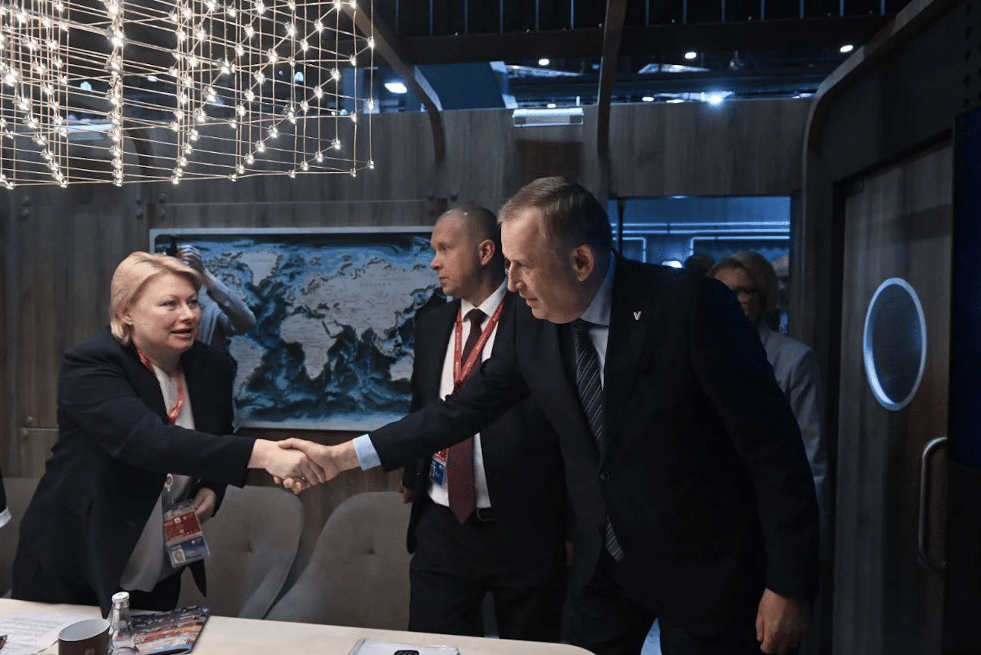 Links eine blonde Frau, rechts ein Mann. Sie schütteln sich die Hand.