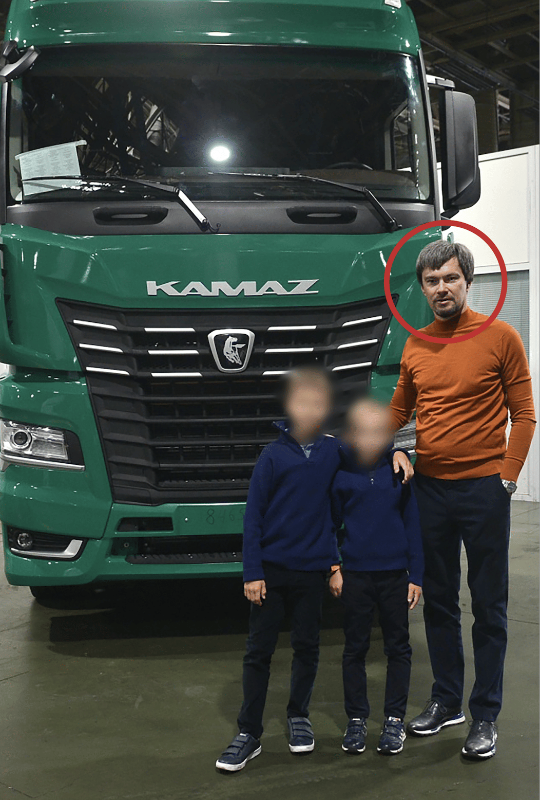 Ein Mann mit zwei Kindern steht vor einem LKW