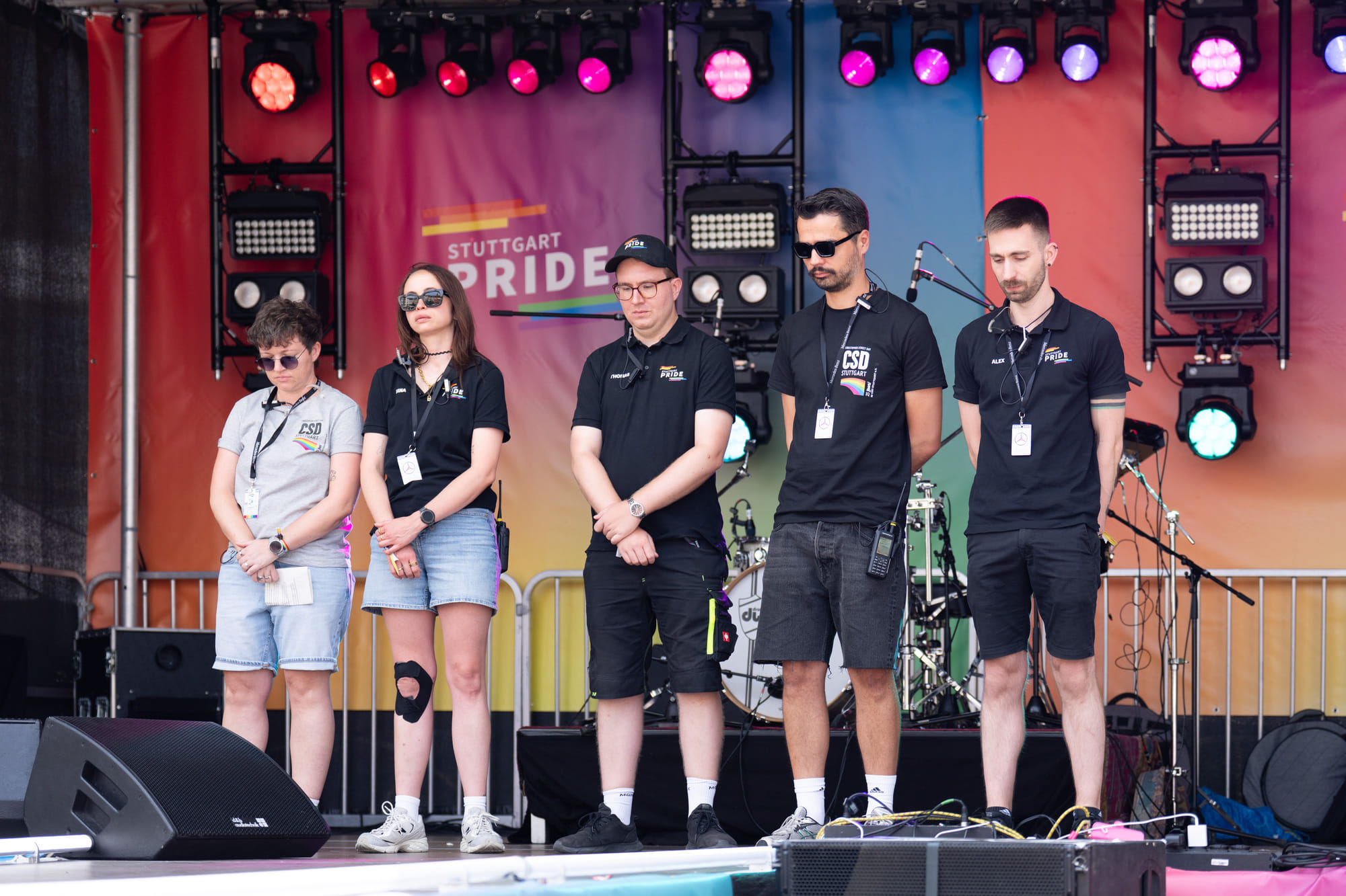 Die Vorstandsmitglieder des Stuttgarter CSD-Vereins um Lars Lindauer (zweiter von rechts) stehen mit gesenkten Köpfen auf der Bühne, um der Opfer des Anschlags auf den CSD in Berlin zu gedenken. 