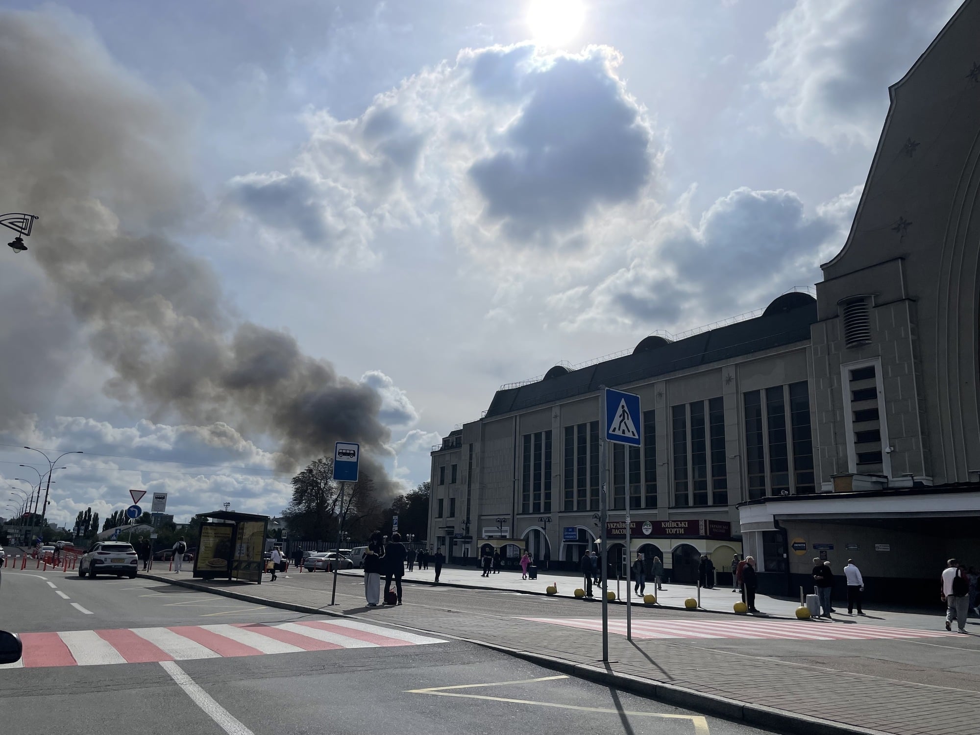 Eine Straße und ein Gebäude. Dahinter steigt eine große Rauchwolke auf.