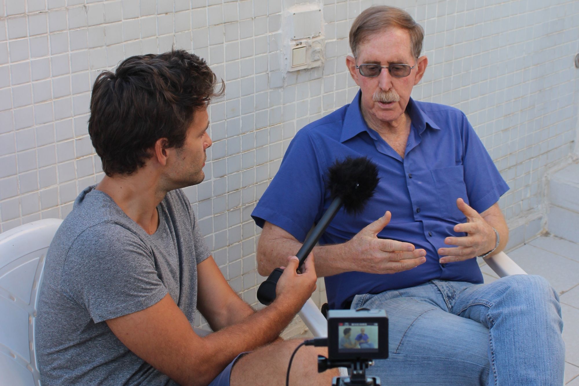 Dan Schueftan im Gespräch vor einer kahlen, weißen Wand, während die Dunkelheit einbricht.