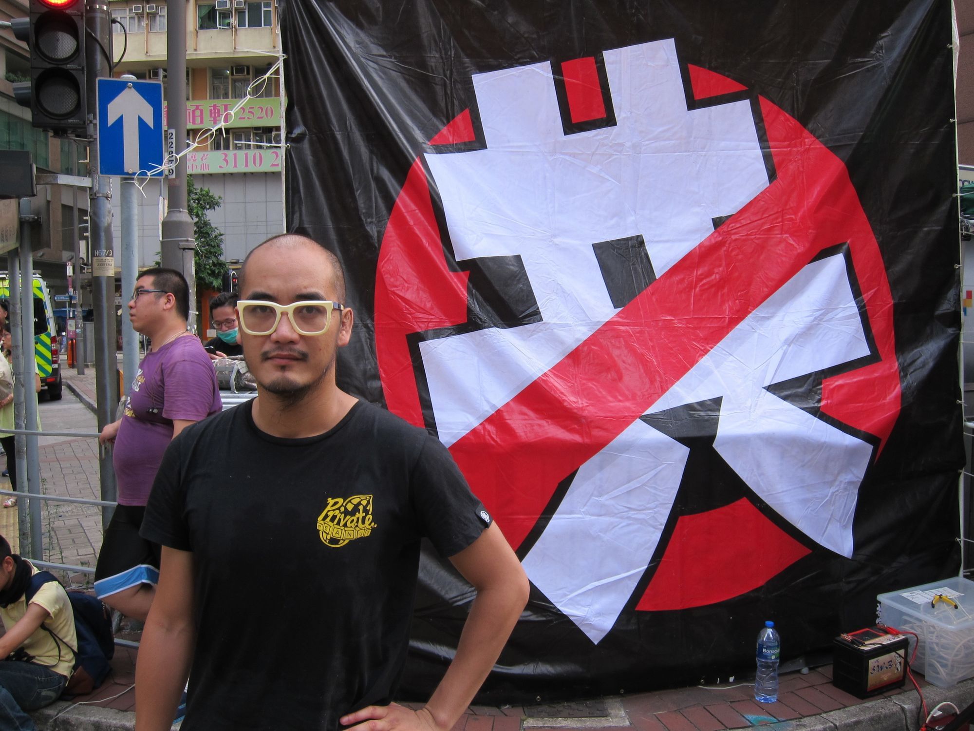 Wong Yeung-tat vor einem Anti-Kommunismus-Plakat