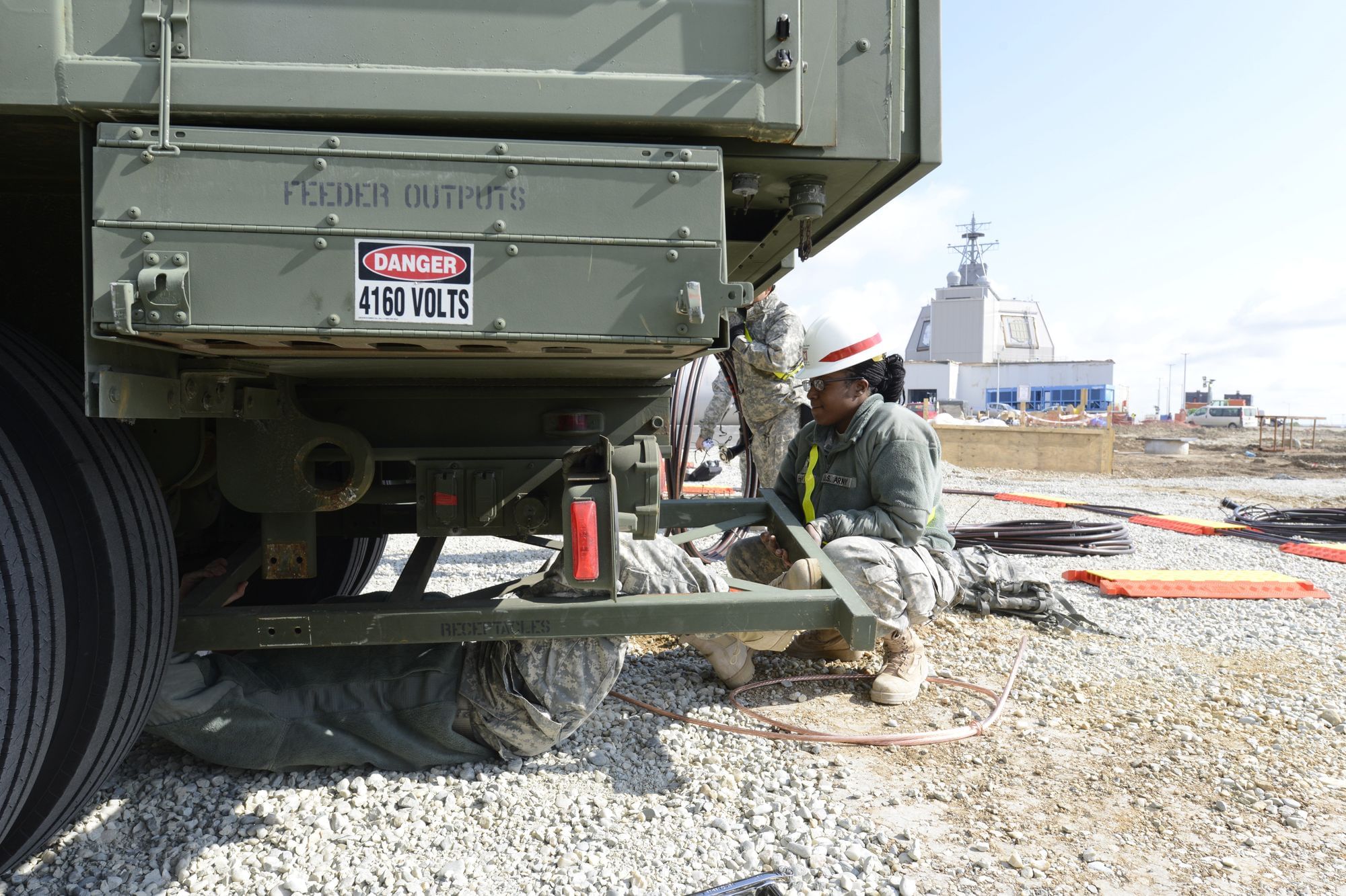 Eine US-Soldatin arbeitet auf einer Basis in Rumänien mit einem Kameraden an einem Generator. Im Hintergrund ist ein Raketenabwehrsystem zu sehen, das vor wenigen Wochen scharfgeschaltet wurde.