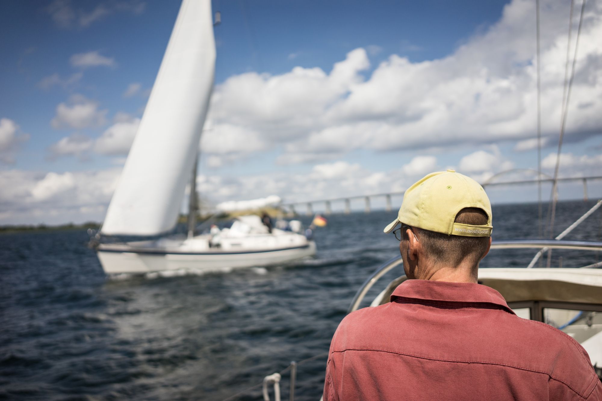 Ben Hadamovsky beobachtet ein Boot aus der schwedischen Werft Hallberg-Rassy als es vor einer Brücke nahe der Insel Fyn wendet. Ben kennt alle Bootstypen in- und auswendig. Das Experiment ist für ihn der Versuch, Geld zu verdienen mit etwas, was Spaß macht.