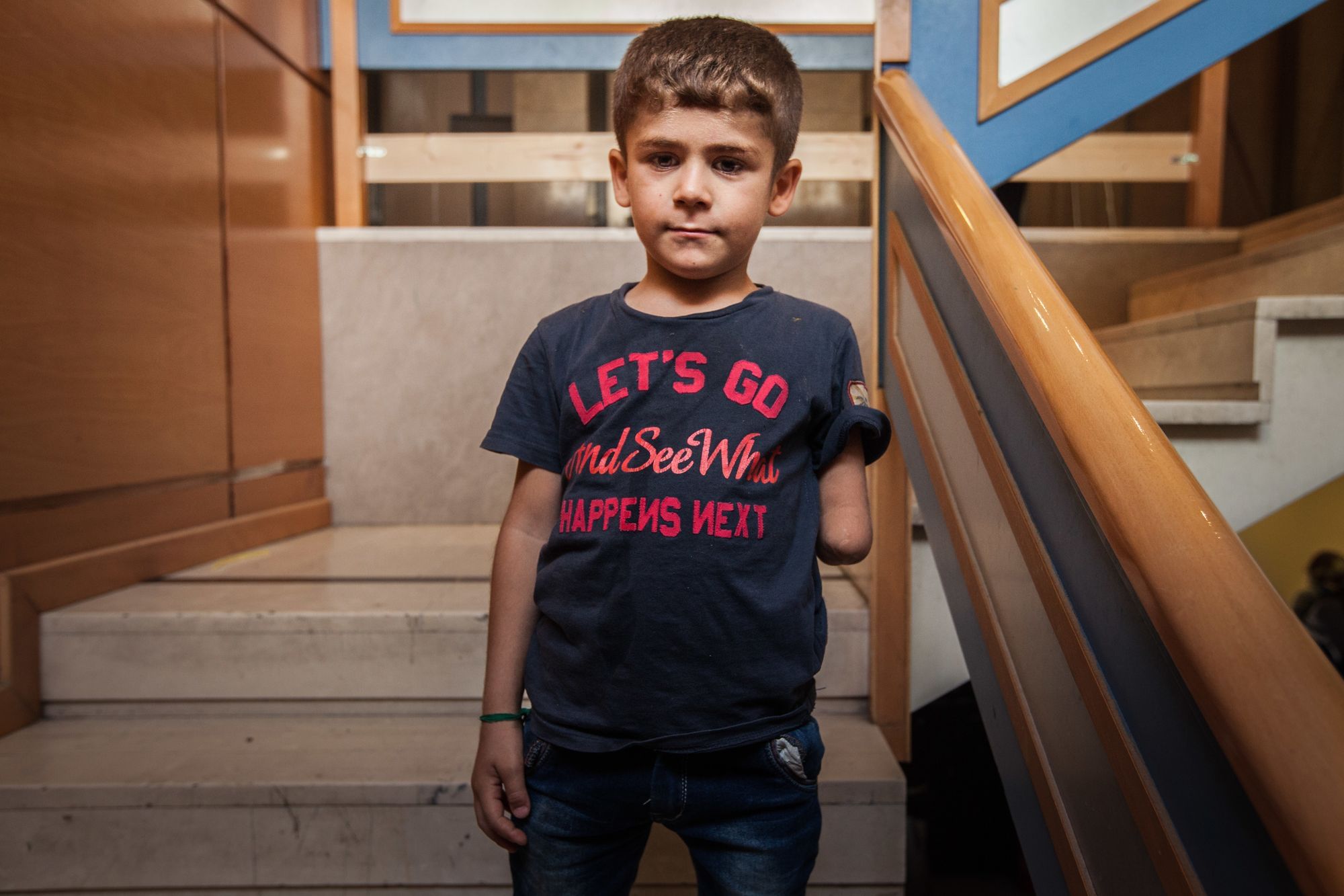 Dieser syrische Junge hat seinen Arm bei einem Bombenabwurf in seinem Heimatland verloren. Auf seinem T-Shirt steht: "Let's go and see what happens next."