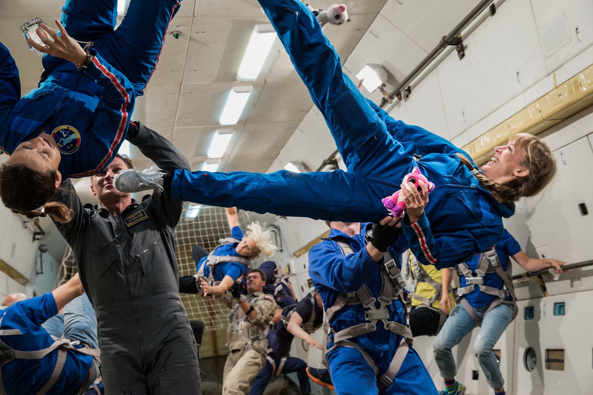 Man sieht ein Team an Astronaut:innen schwerelos durch den Raum segeln
